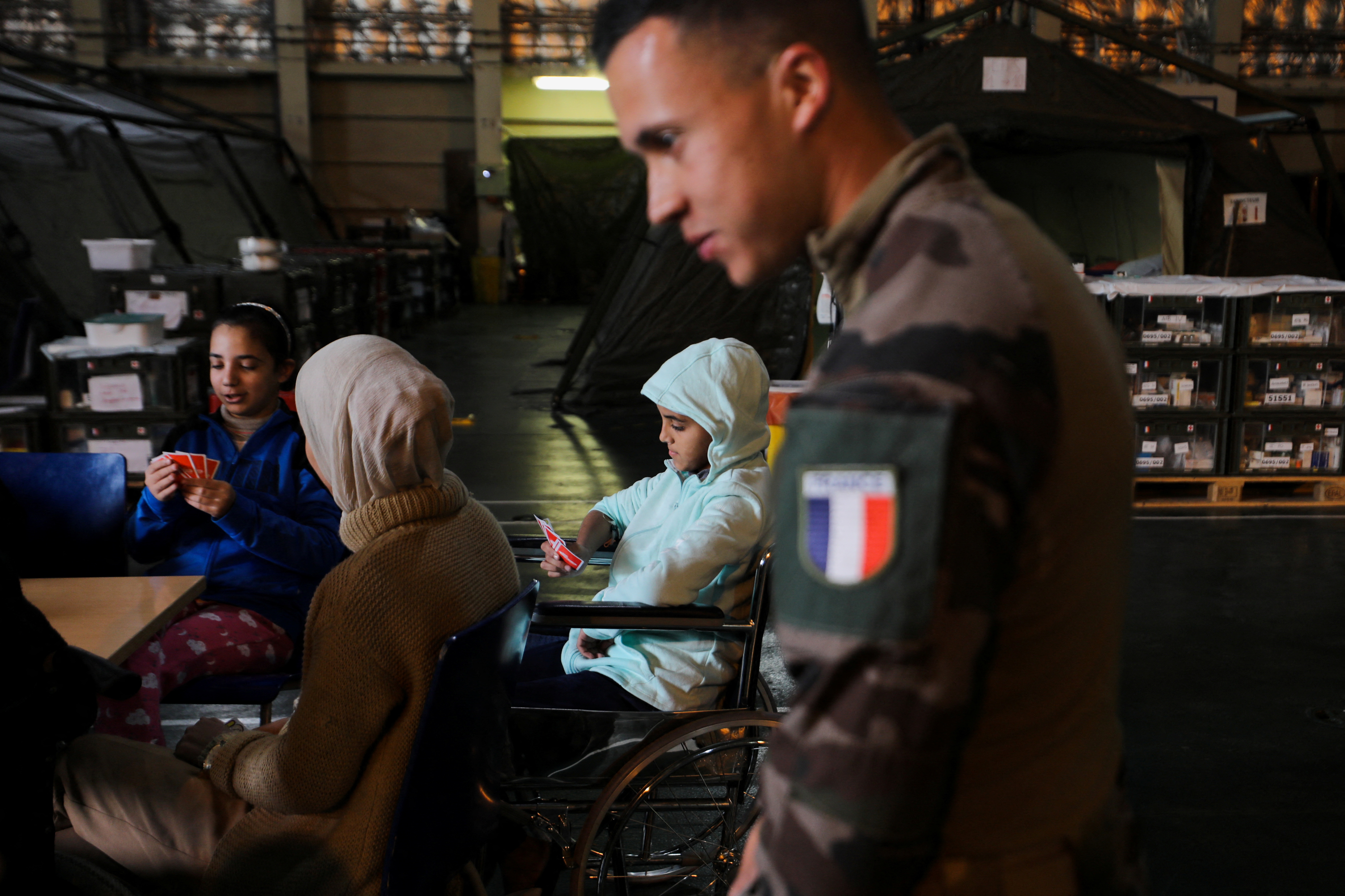 A French naval officer stands next to a wounded Palestinian child at the hospital onboard the French ship amphibious helicopter carrier Dixmude as it docks, amid the ongoing conflict between Israel and the Palestinian Islamist group Hamas, in the city of Al-Arish, Sinai peninsula, Egypt, January 21