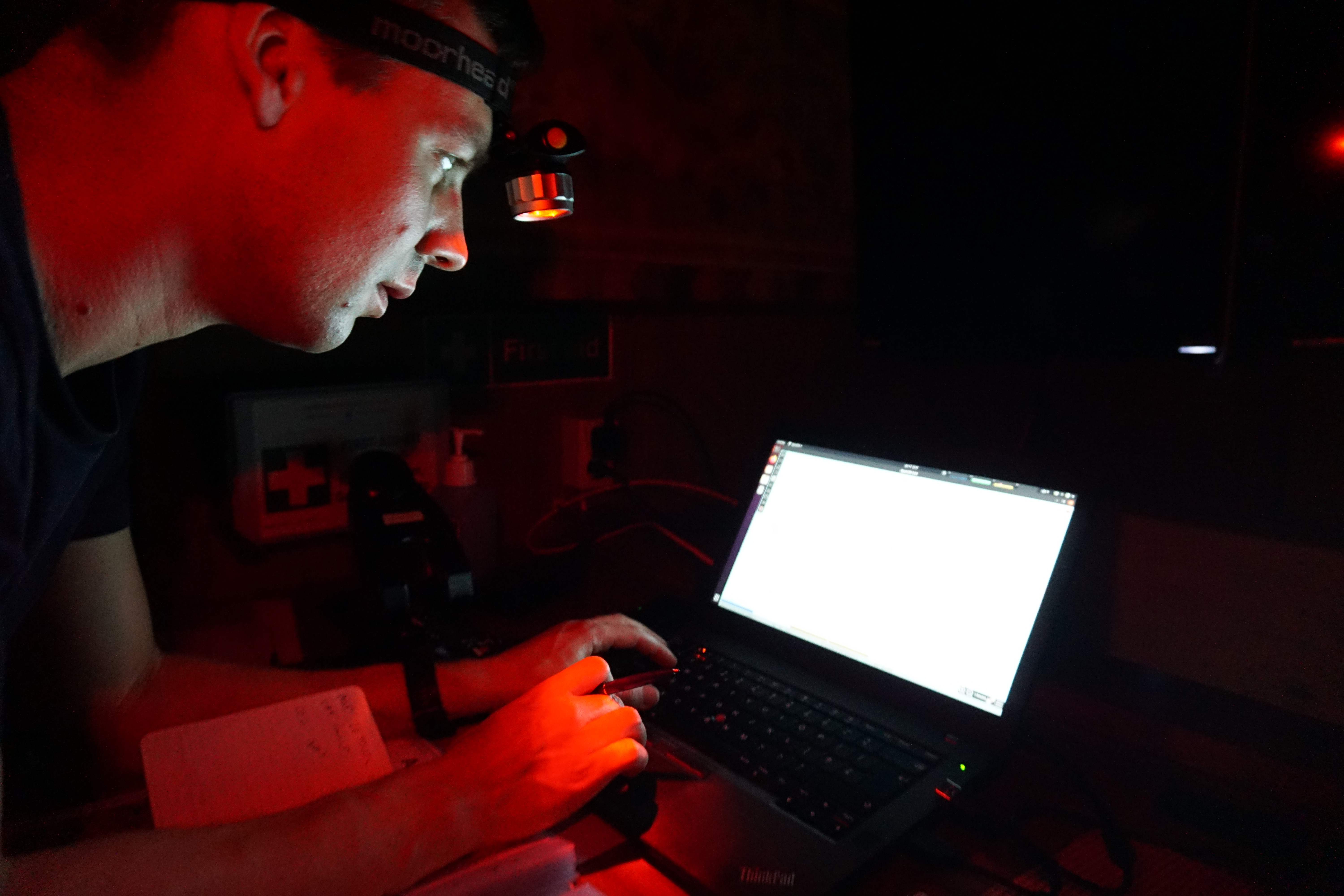 Man leaning towards glowing screen in dark room