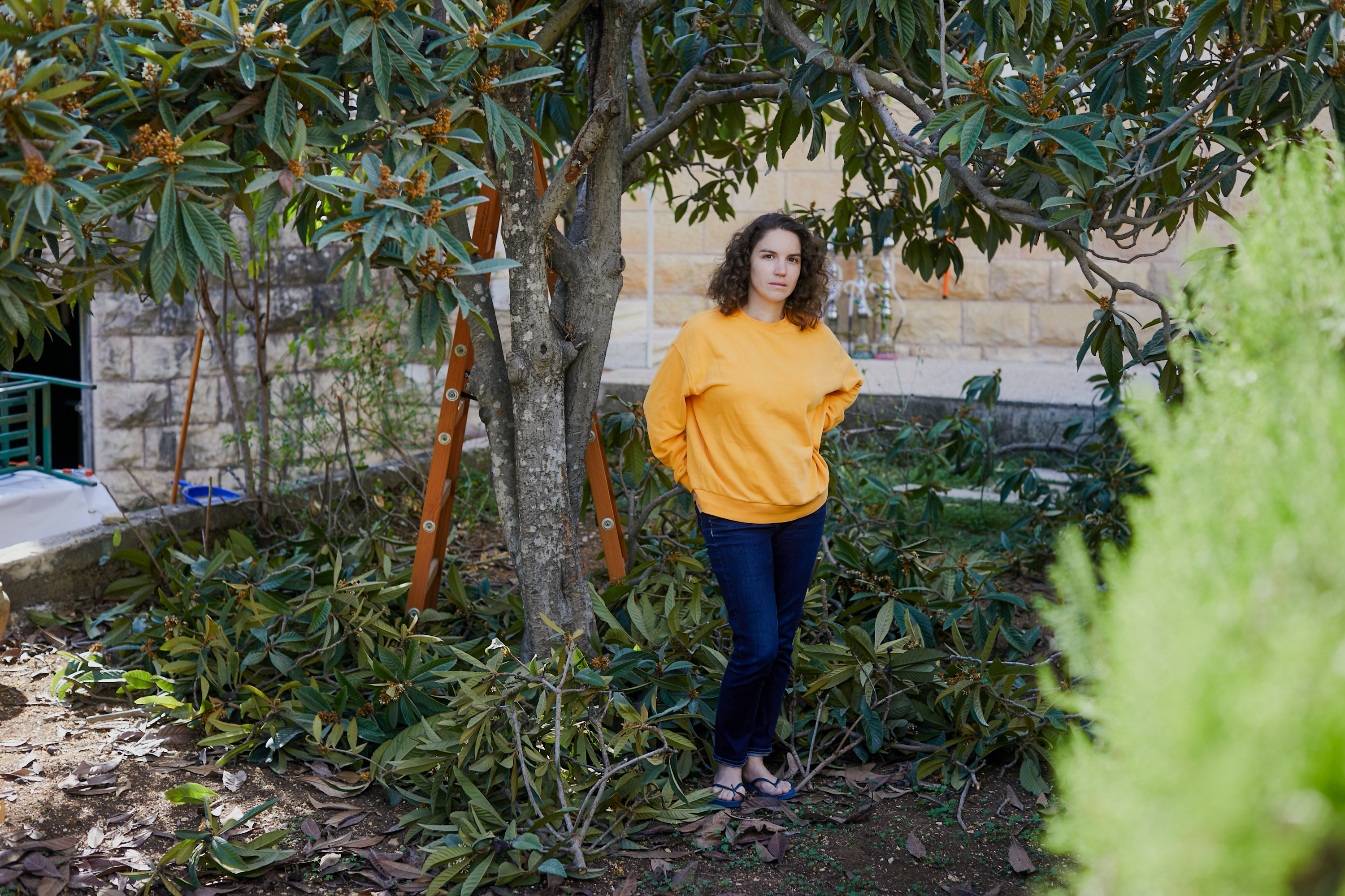 Ines in yellow sweatshirt in an orchard