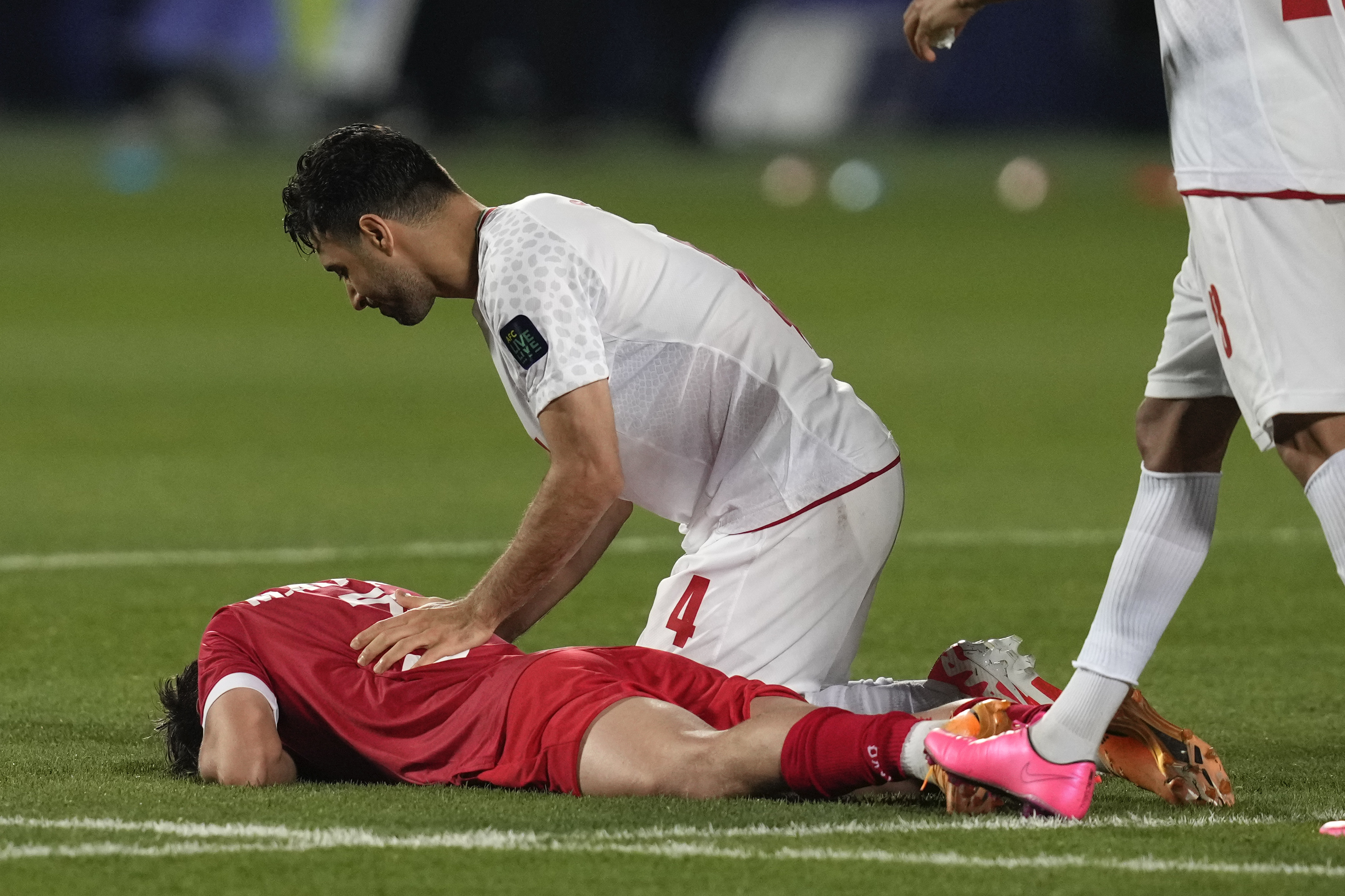 Syria's Mouaiad Alajaan lies on the ground as Iran's Shojae Khalilzadeh comforts him