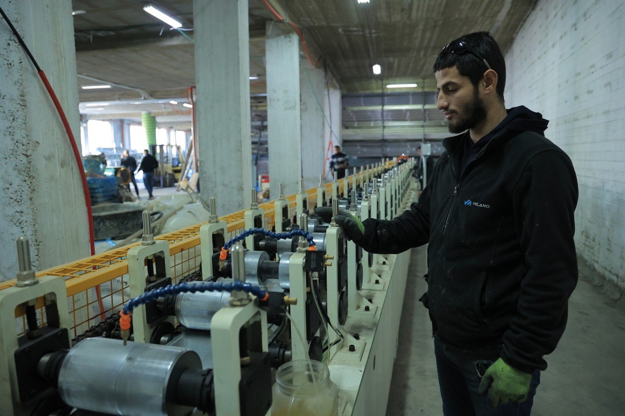 Rakan stands by a machine spooling aluminium