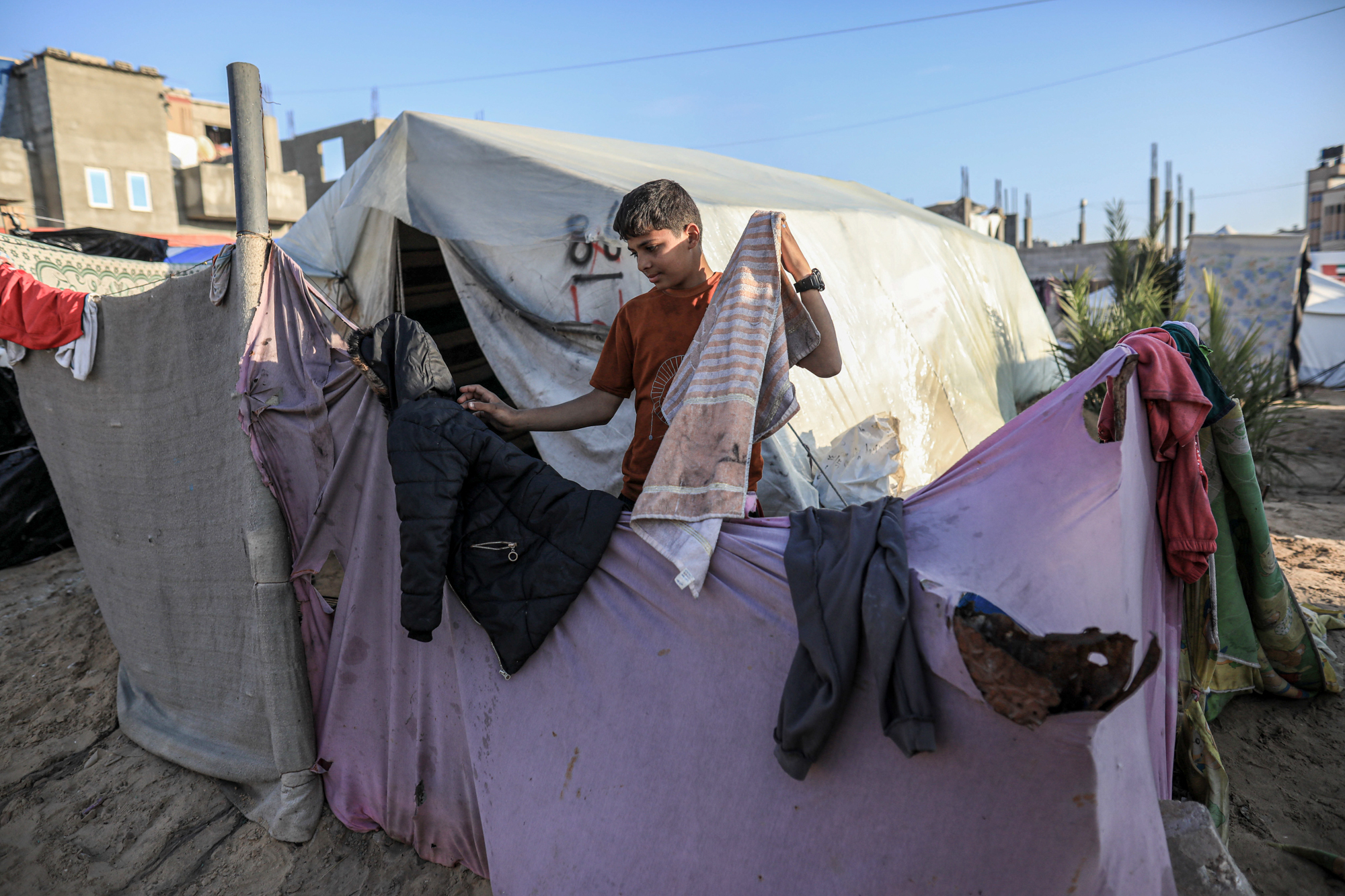 Mohammad pulling blothing off a sheet stretched between poles