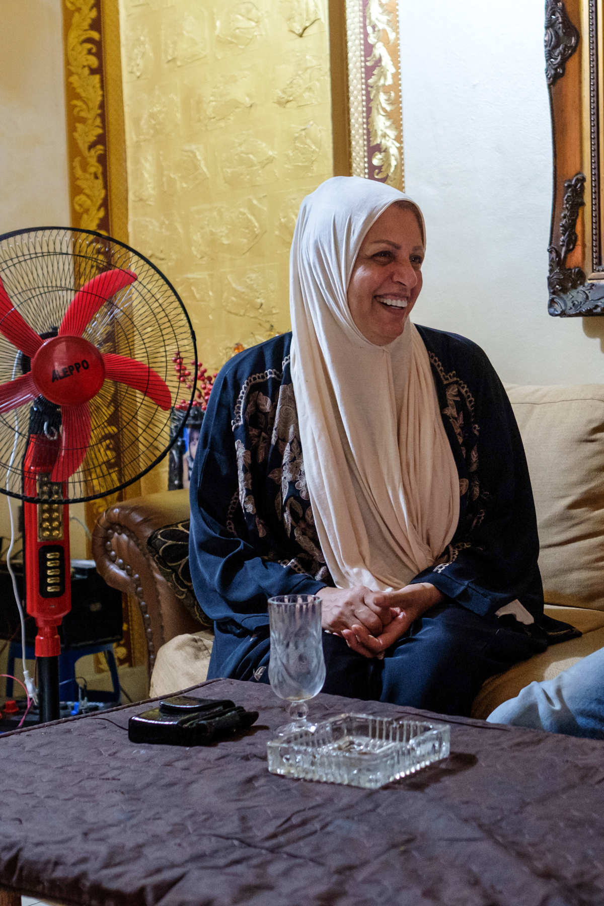 Em Hadi and Abou Hadi in their living room, one of Abou Hadi's carefully positioned fans beside them