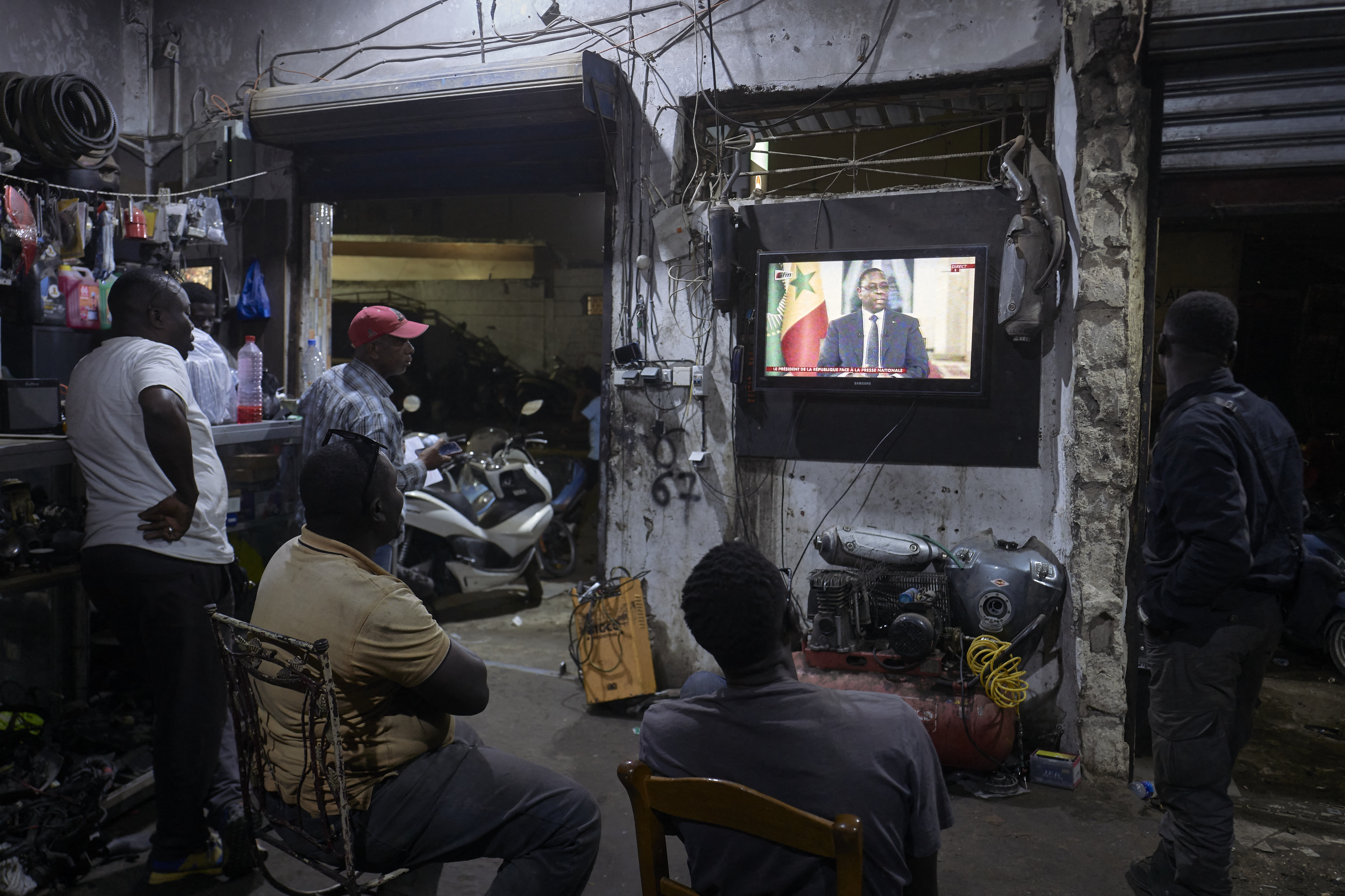 People watch the Senegal's President Macky Sall during a live press conference broadcast on the national television, in the district of Medina in Dakar on February 22