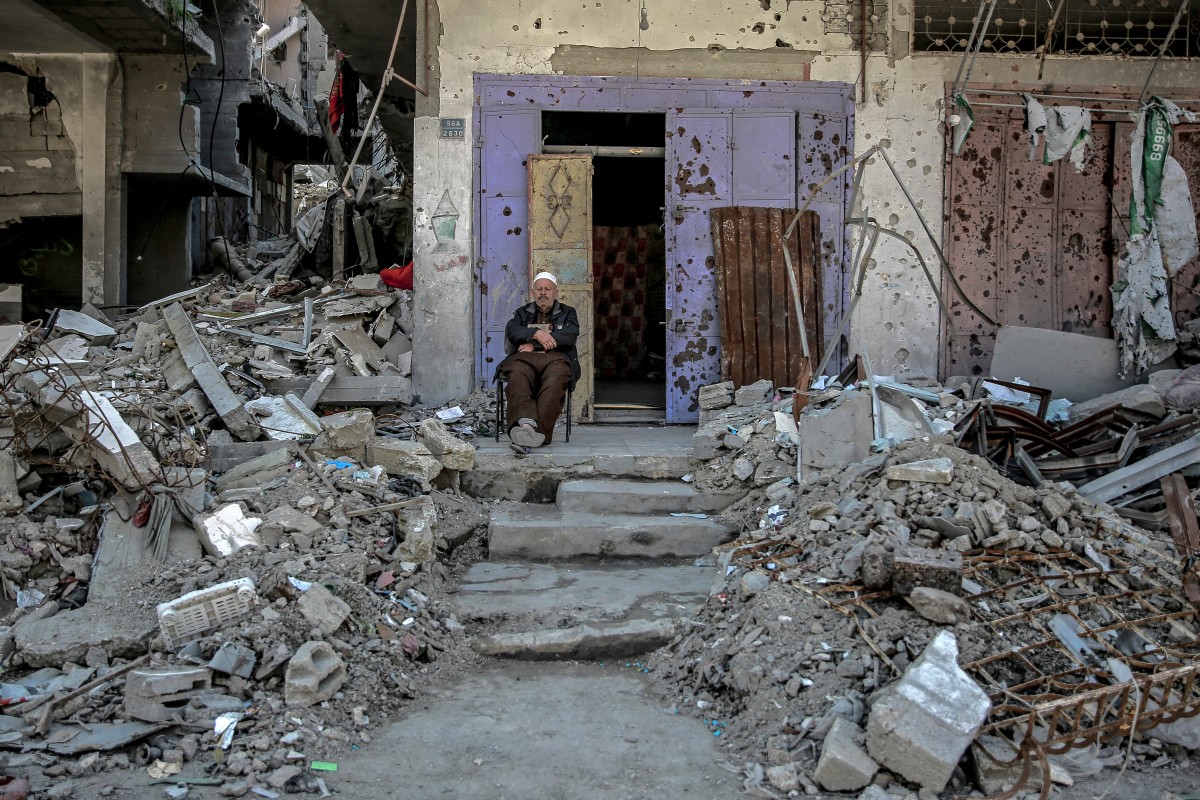 A Palestinian man sits amid debris