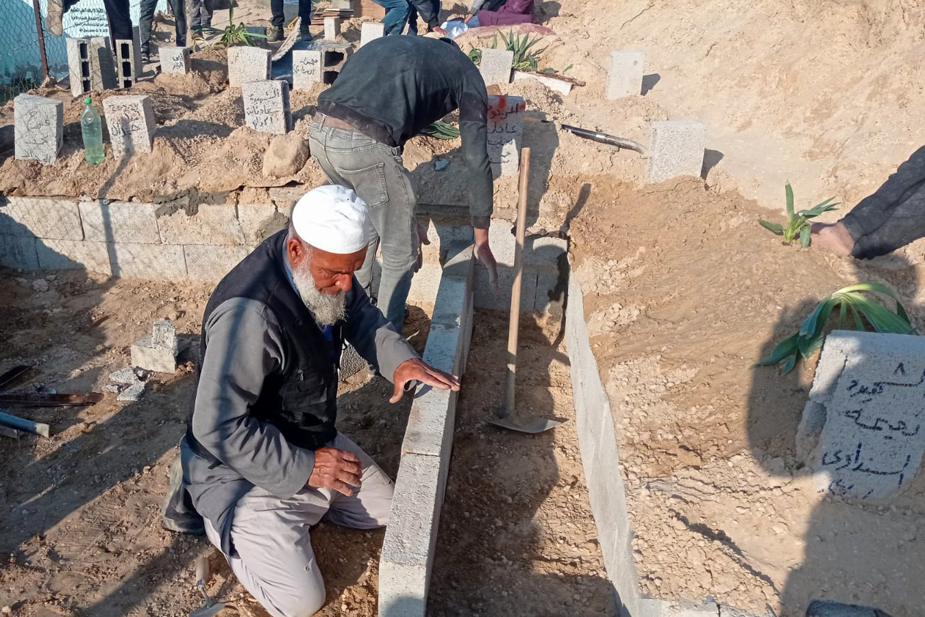 Abu-Jawad building an individual grave with one of his men