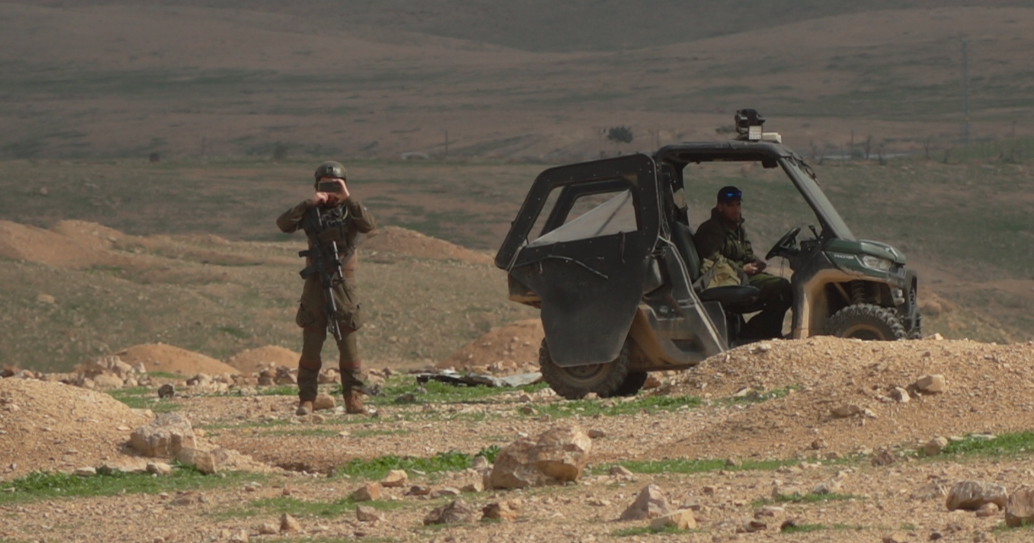 One settler in the ATV and another standing outside taking photos of the crew