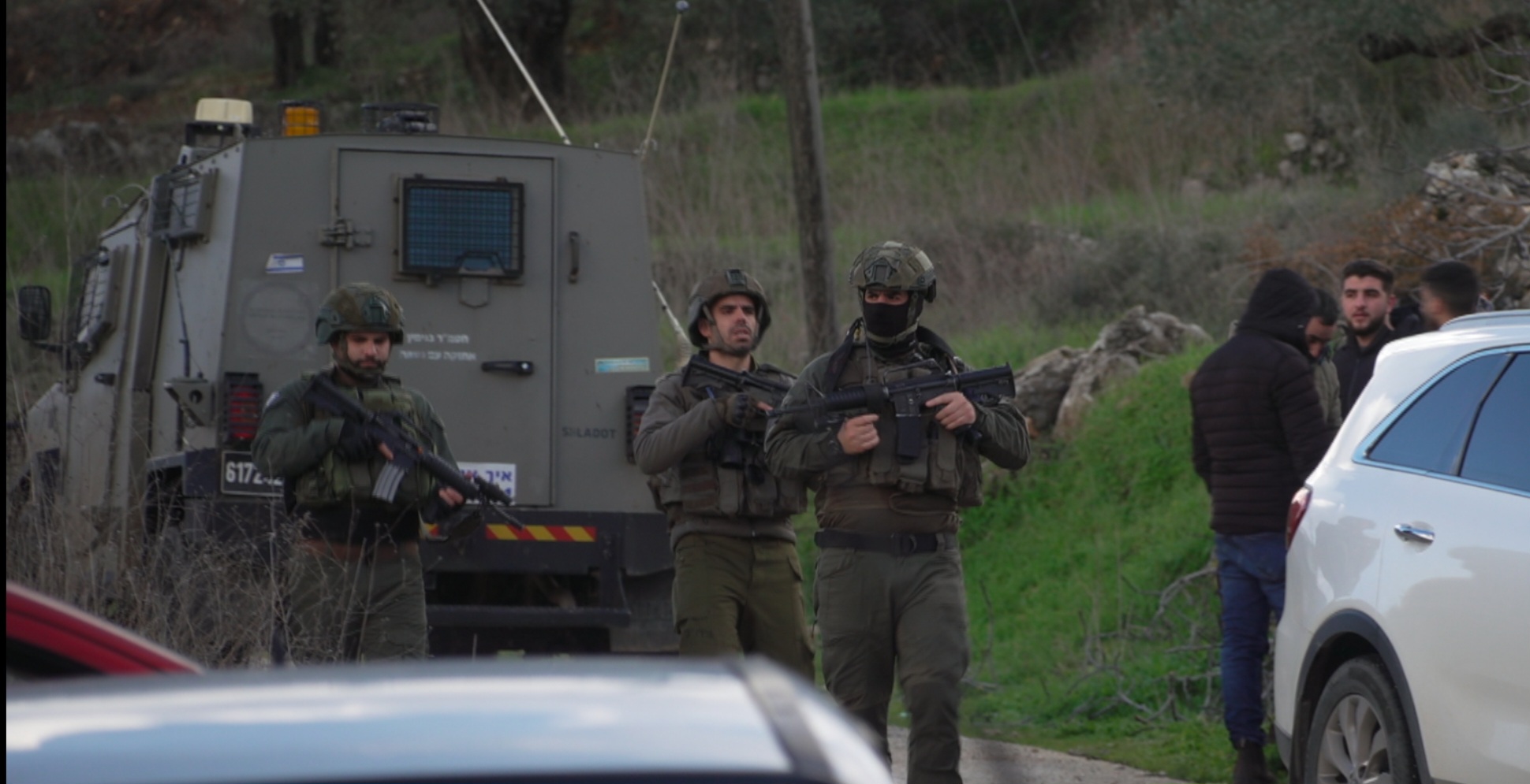 Soldiers waslking out of their armoured vehicle, weapons at the ready