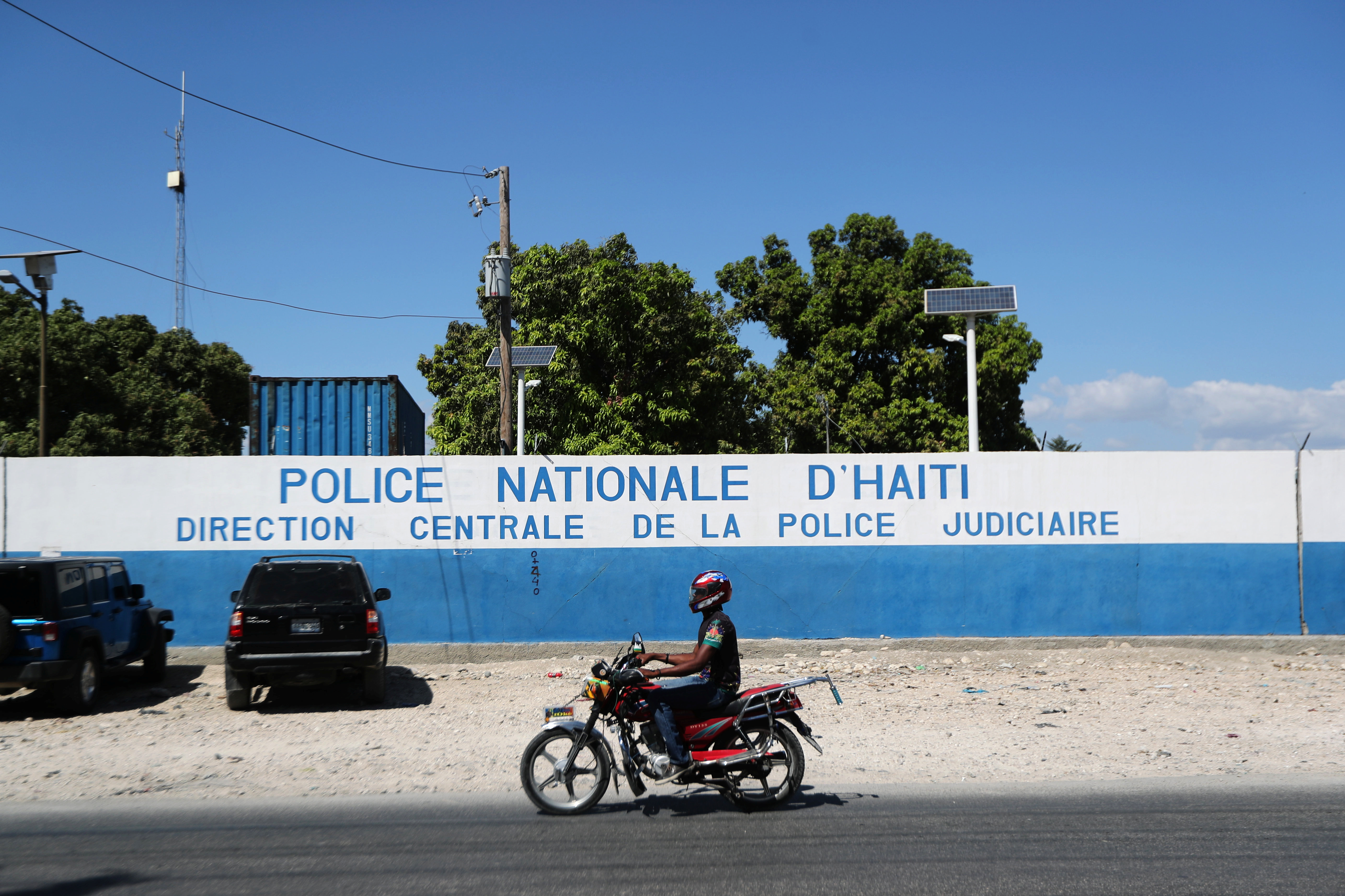 A man rides a bike in front of a main Haitian police station, 