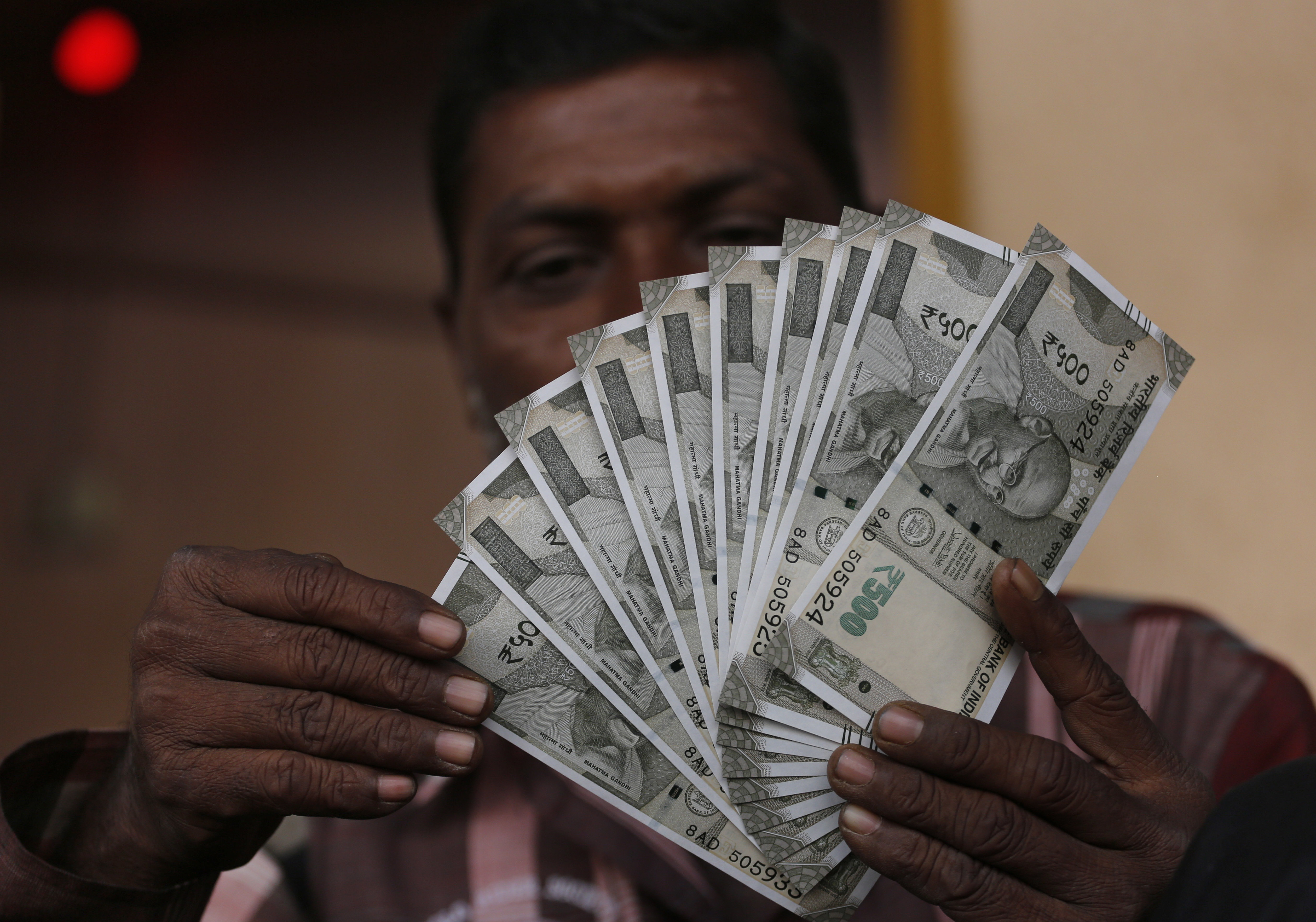 An Indian man makes formations with new currency notes of 500 Indian rupees that he received at an Agriculture Produce Market Committee (APMC) market in Ahmadabad, India, Wednesday, Nov. 23, 2016. Delivering one of India's biggest-ever economic upsets, Prime Minister Narendra Modi on November 8 declared the bulk of Indian currency notes no longer held any value and told anyone holding those bills to take them to banks. (AP Photo/Ajit Solanki)