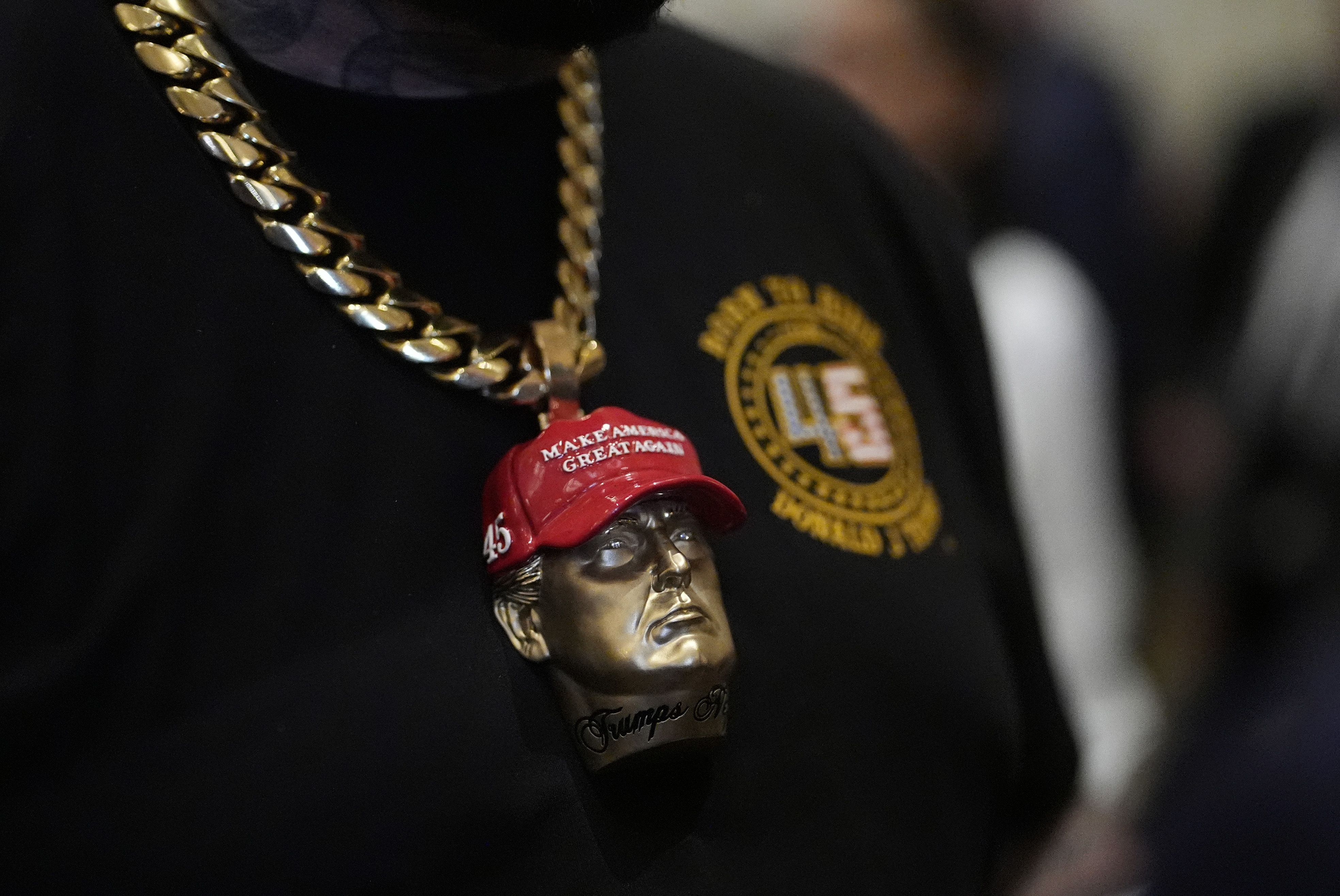 A man wears a Trump head on the end of a chain around his neck in support of the candidate.
