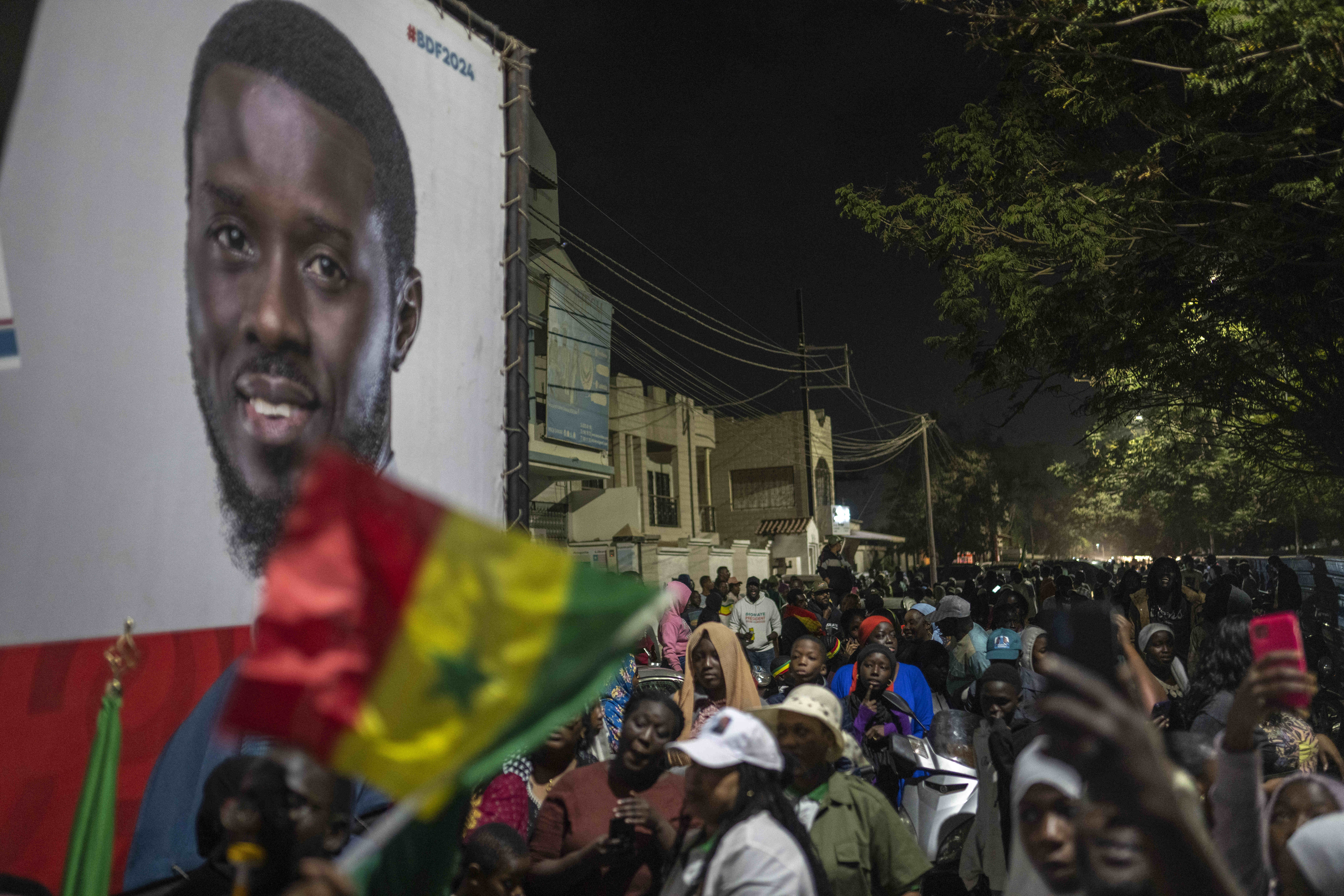 Supporters of presidential candidate Bassirou Diomaye Faye gather outside his campaign headquarters as they await the results.