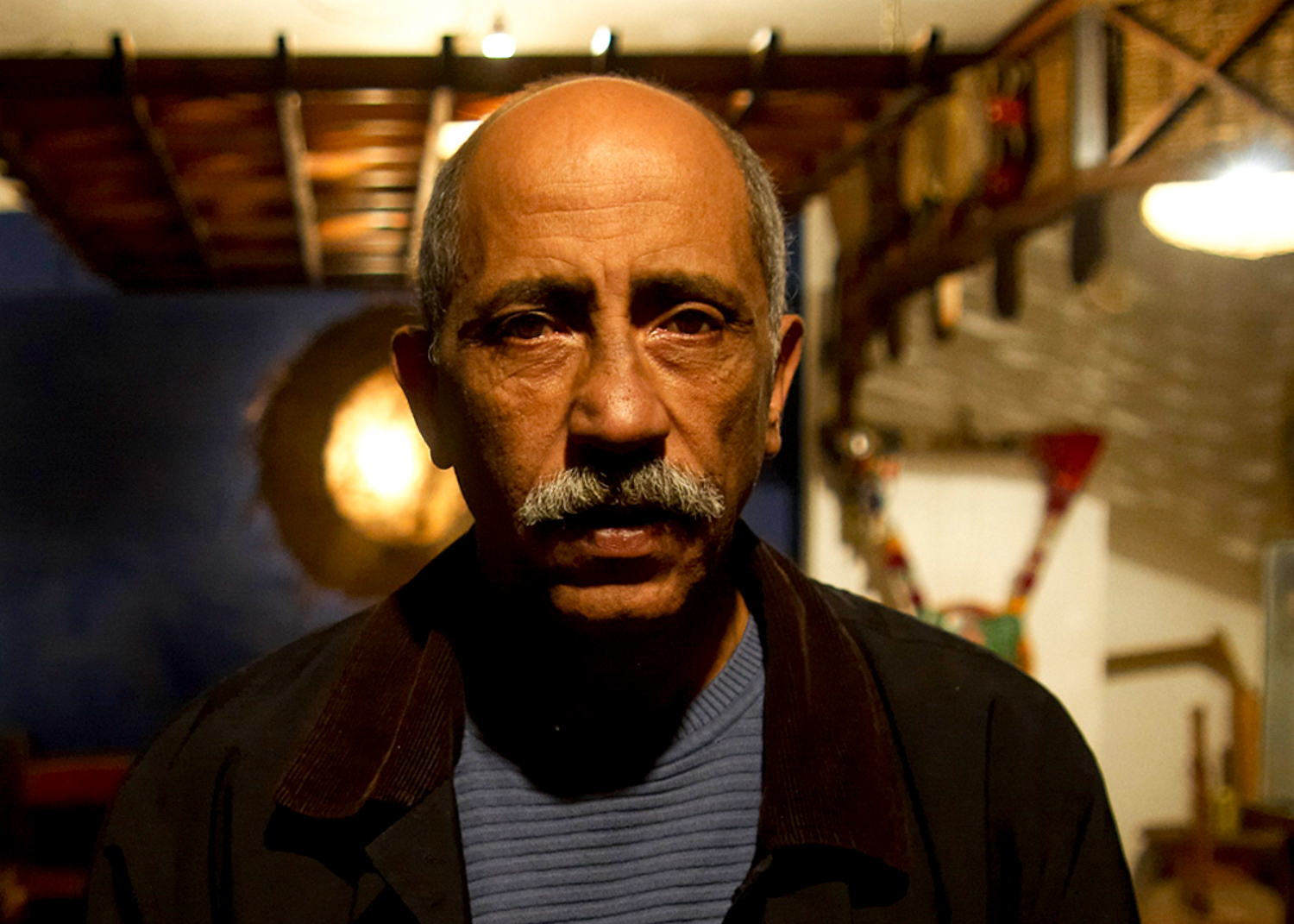 Zakaria looking at the camera, instruments out of focus on the walls behnd him