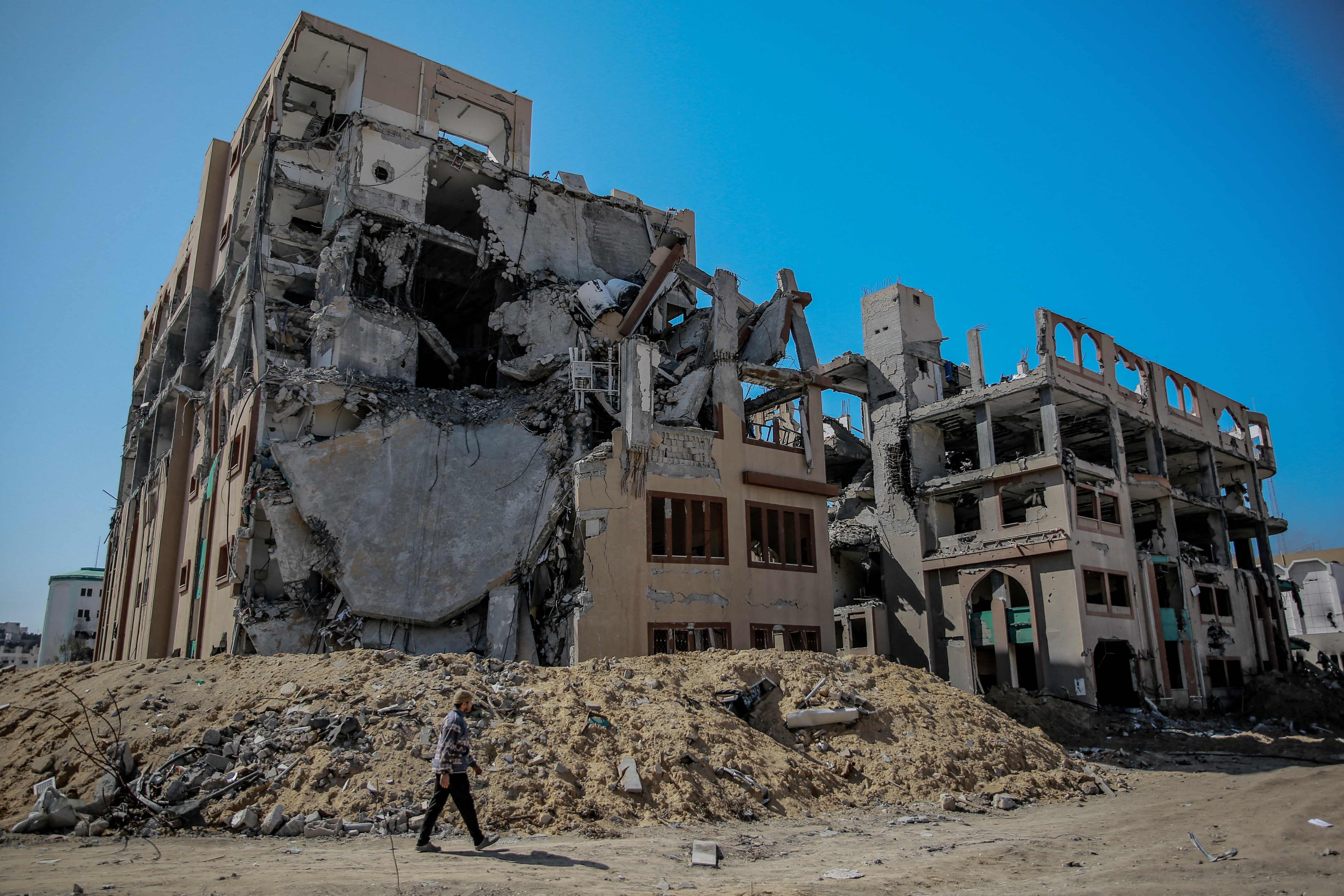A Palestinian man walks past a heavily damaged building of the author's alma mater, Islamic University of Gaza [UIG}, in Gaza City, on February 15, 2024[AFP]