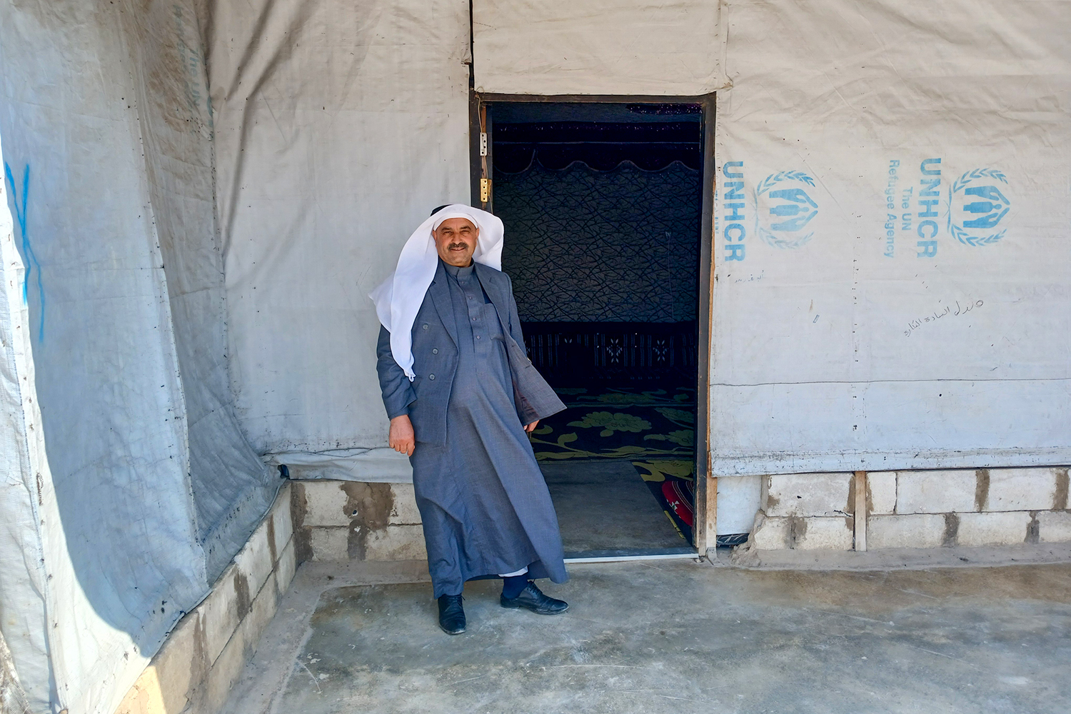 Man in traditional Syrian dress stands in front of a doorway