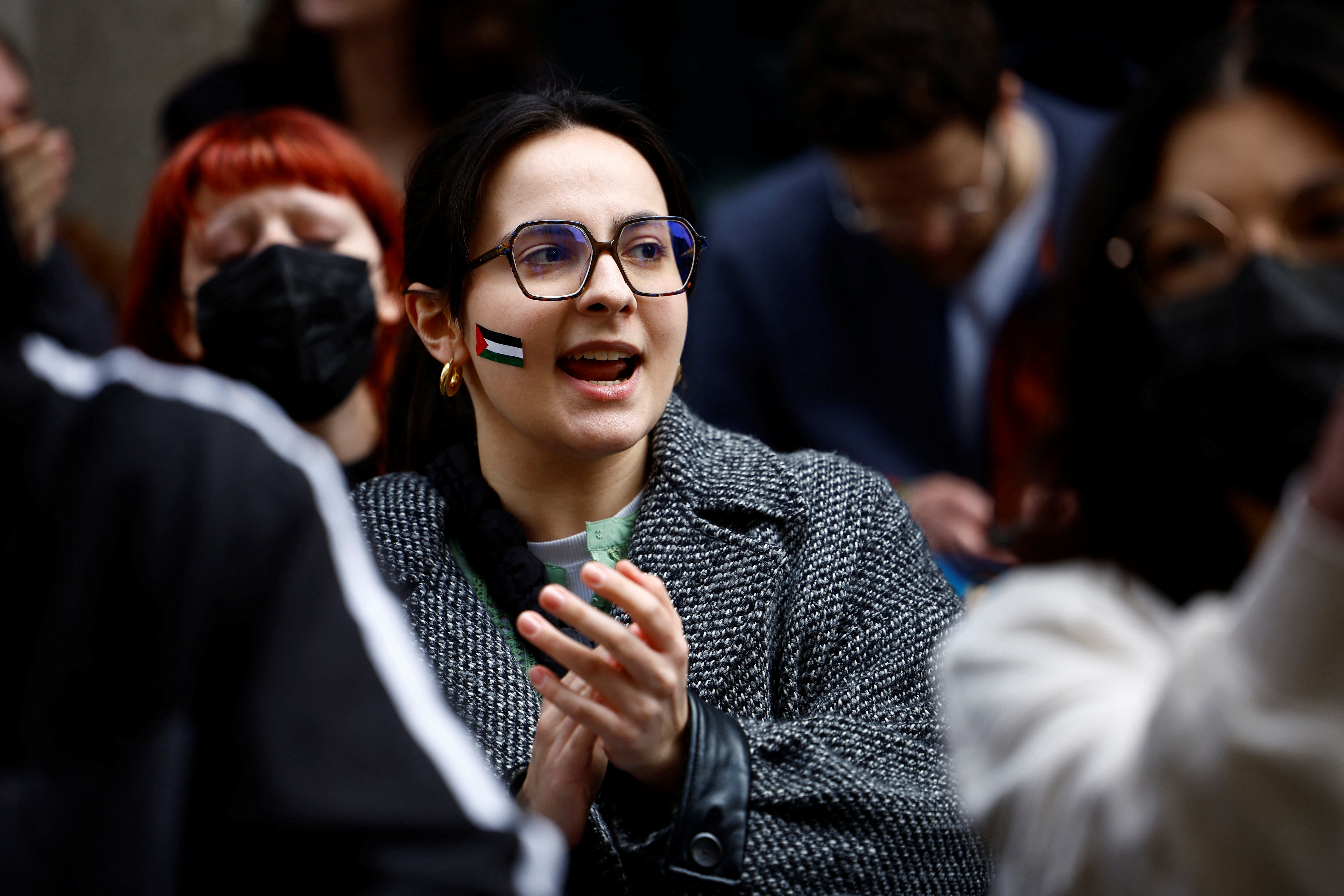 A student with a Palestinian flag painted on her face attends a protest in front of the Sorbonne University