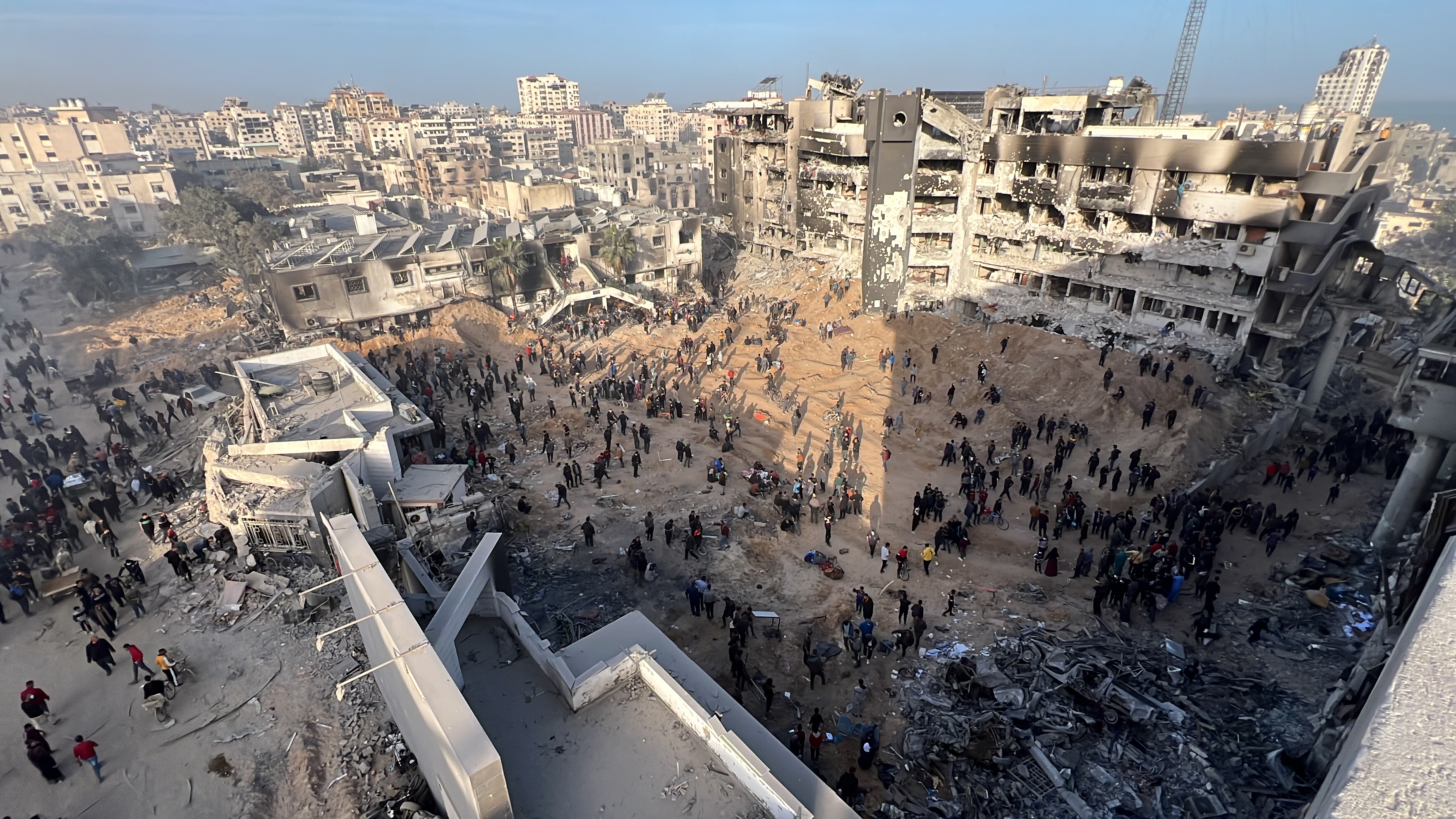Palestinians gather around the burned and destroyed Al-Shifa Hospital