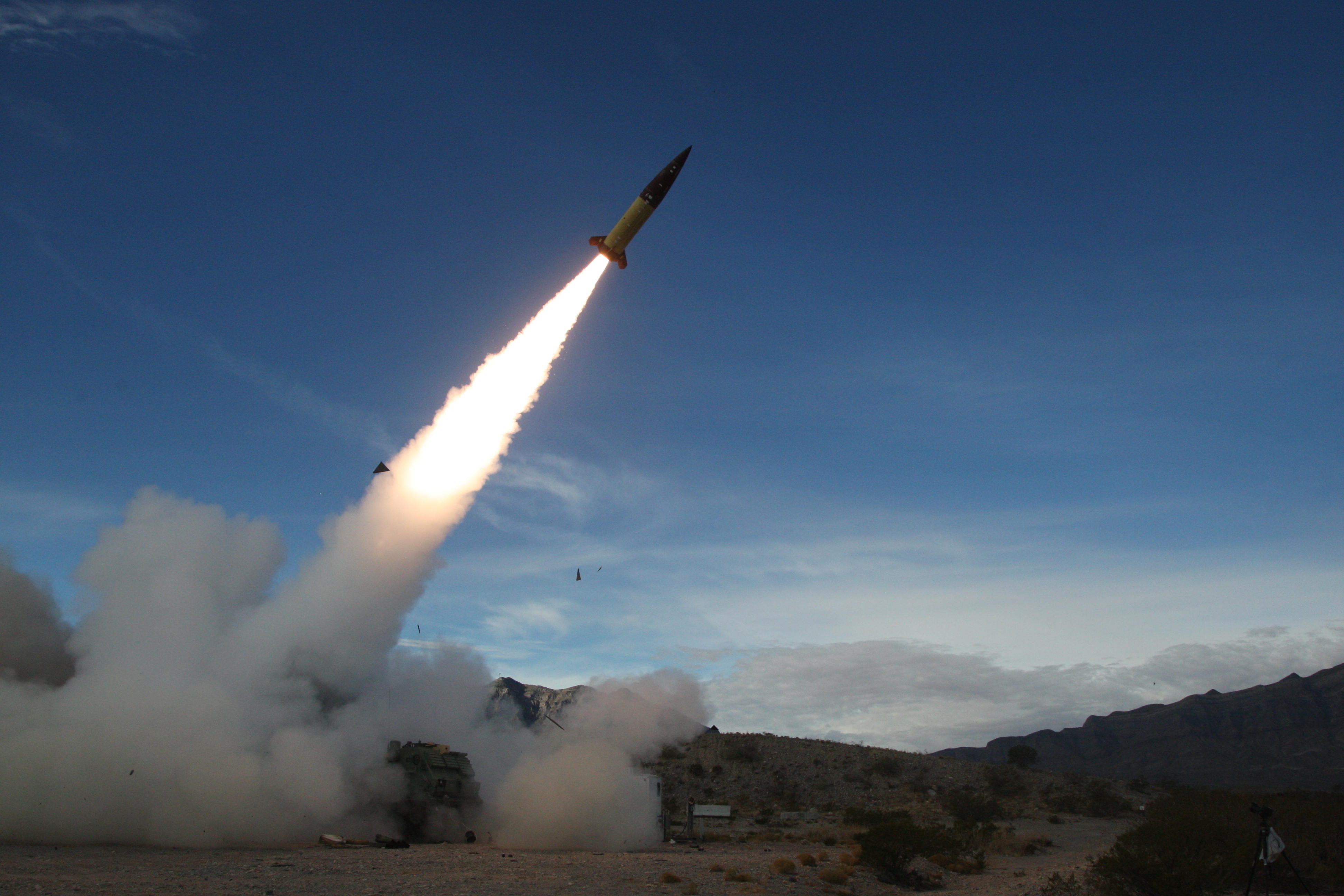 US soldiers conducting live fire testing of an ATACMS. The missile is taking off at an angle leaving a trail of fire and smoke.