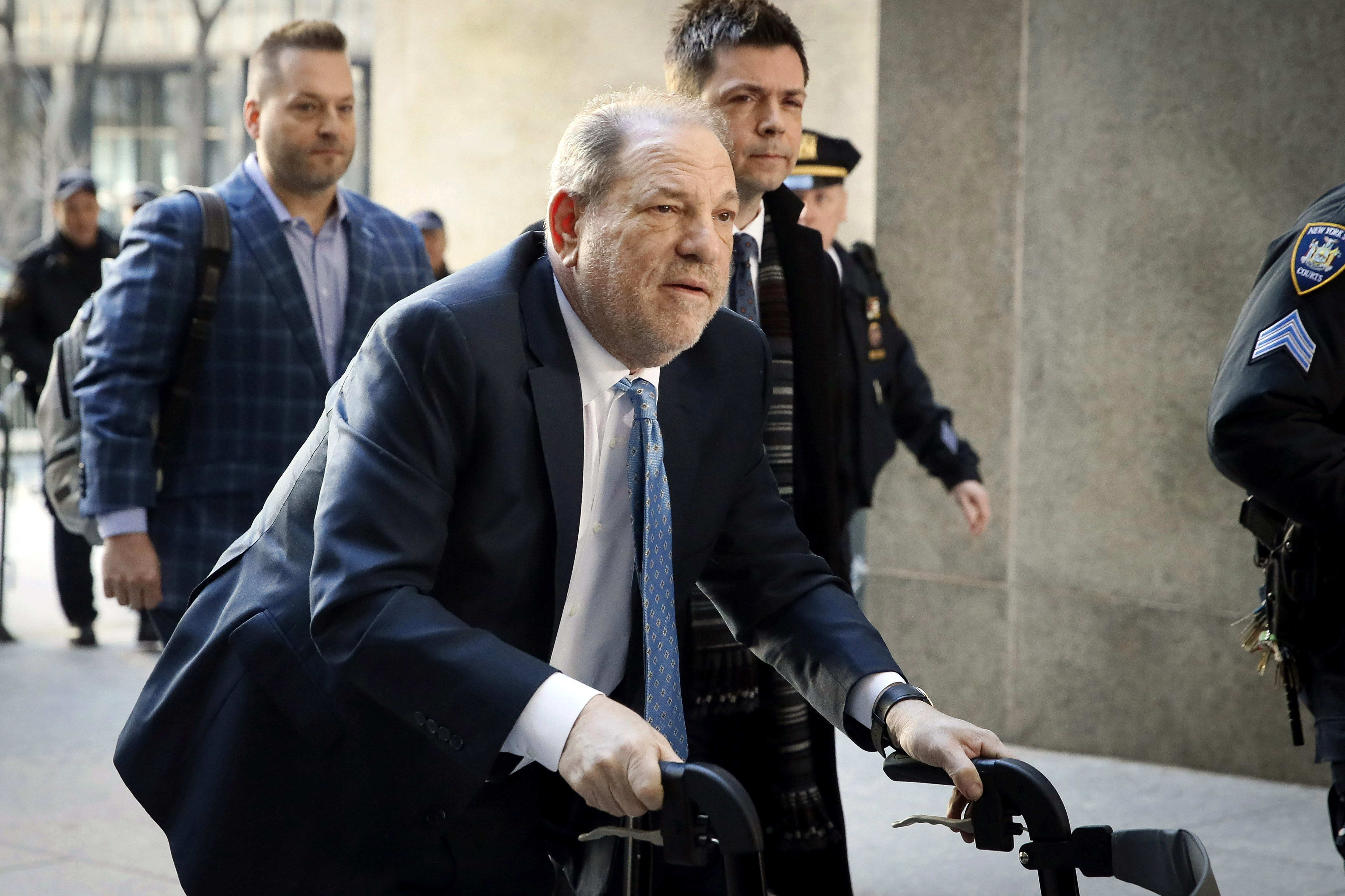 Weinstein arrives at a courthouse with a supporting wheeler