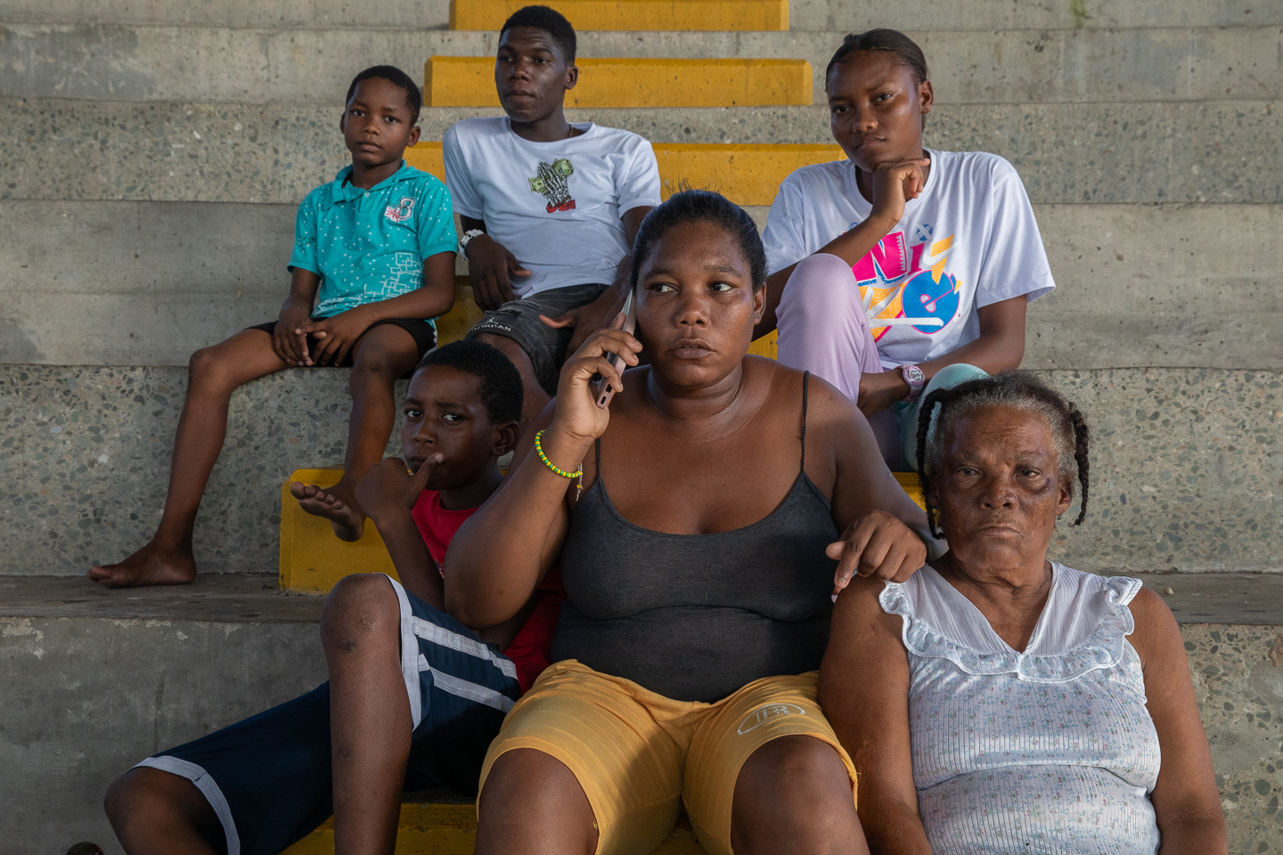 Consuelo Manyoma sits on concrete bleachers surrounded by her children and mother.