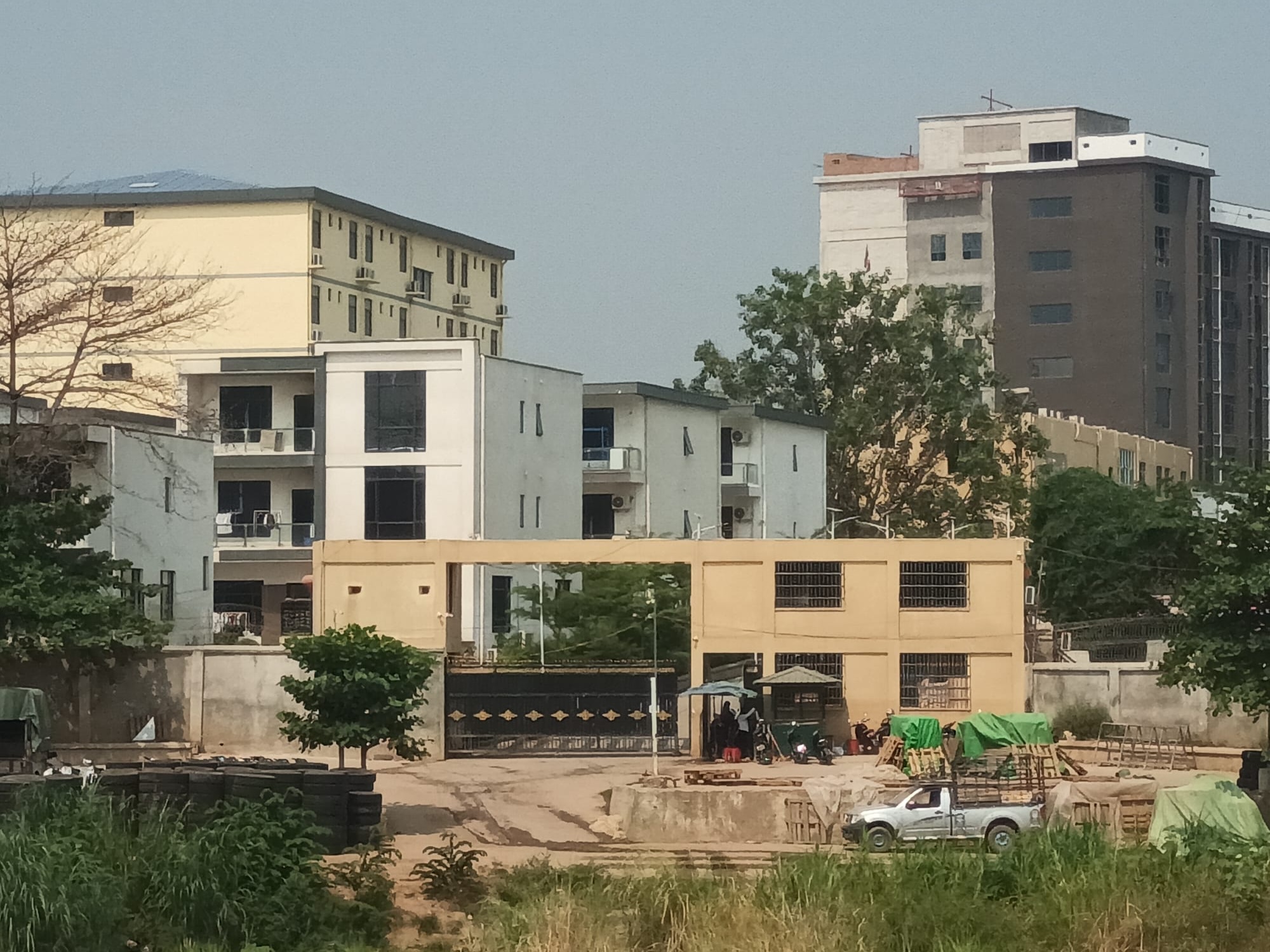 Buildings that make up the 'Dragon Casino' complex. It is on the river. The buildings are cream and squat. There's a high wall with a black gate in front.