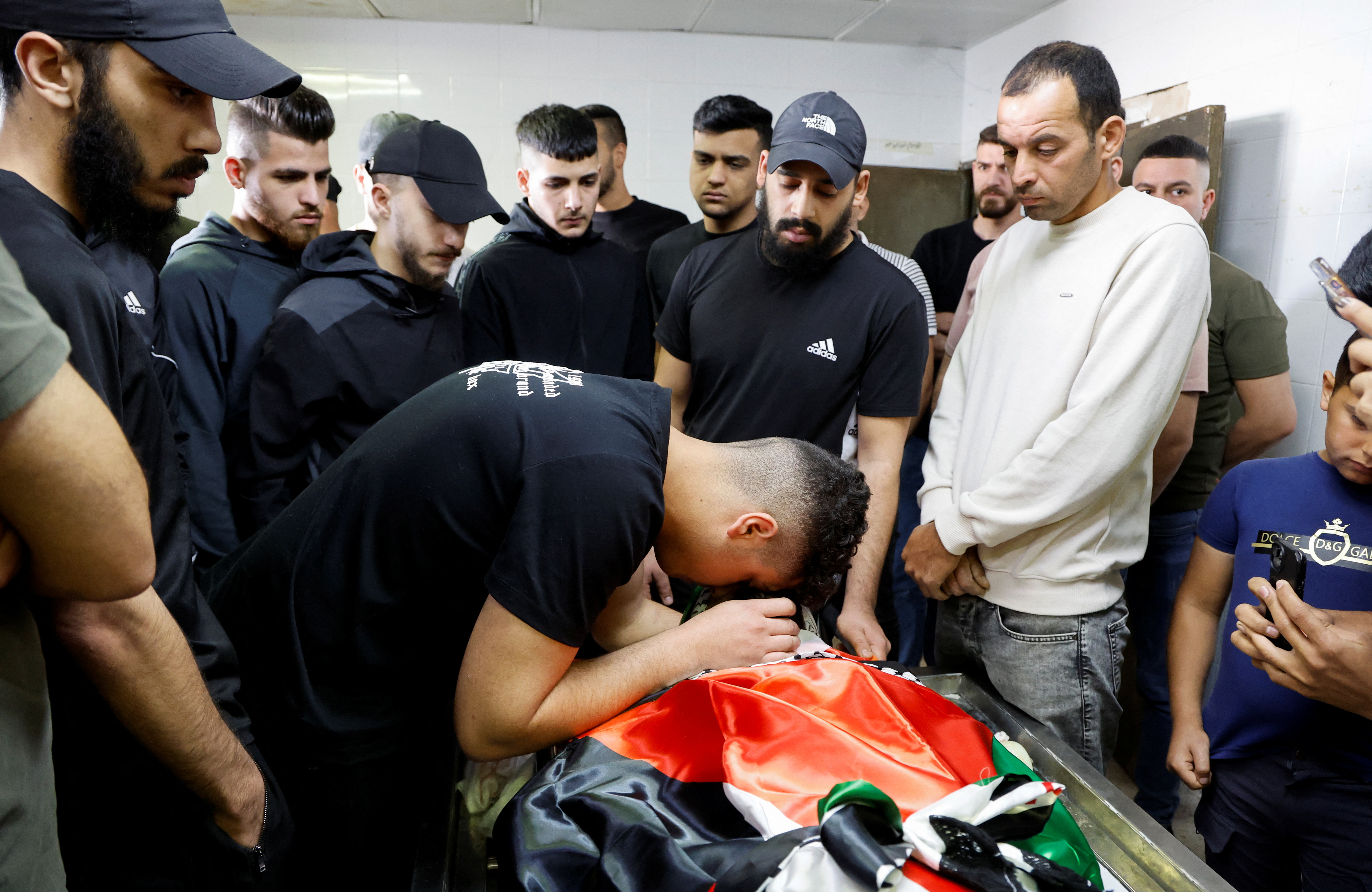 Mourners gather around the body of Palestinian Samer Romana, who was killed in an Israeli raid, during his funeral in Nablus