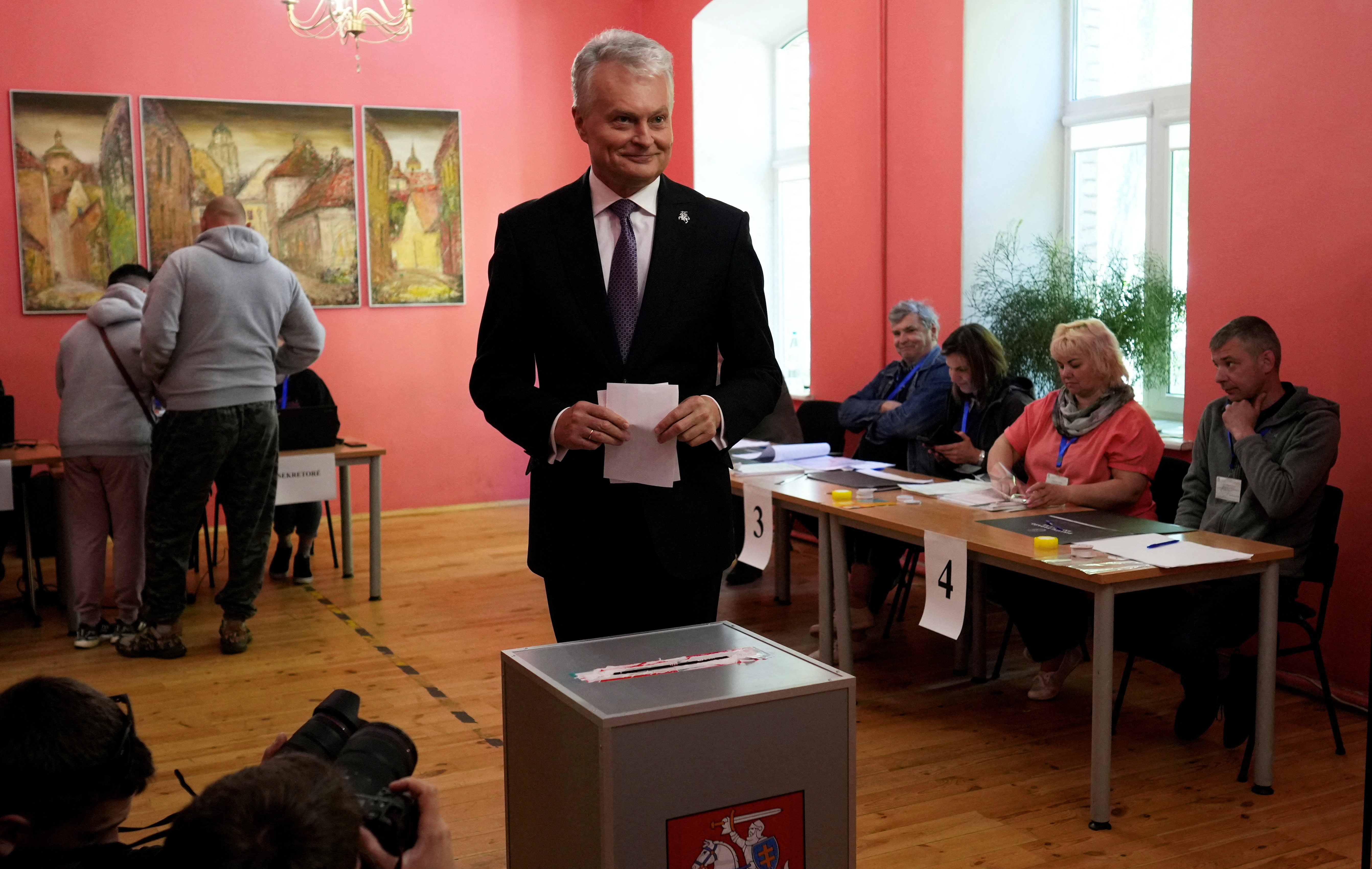 Lithuanian President Gitanas Nauseda casting his ballot. He's dressed in a suit and standing in front of the ballot box and holding his ballot paper.