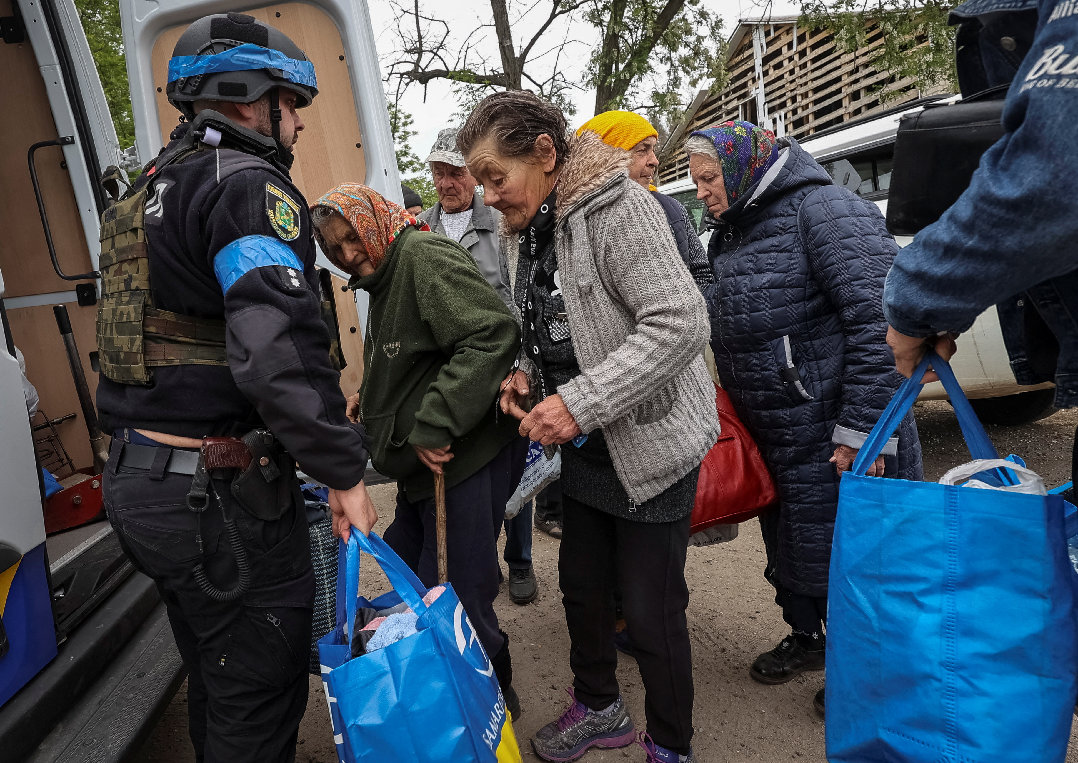 A police officer helps residents from Vovchansk, Ukraine, during Russian attacks in the Kharkiv region