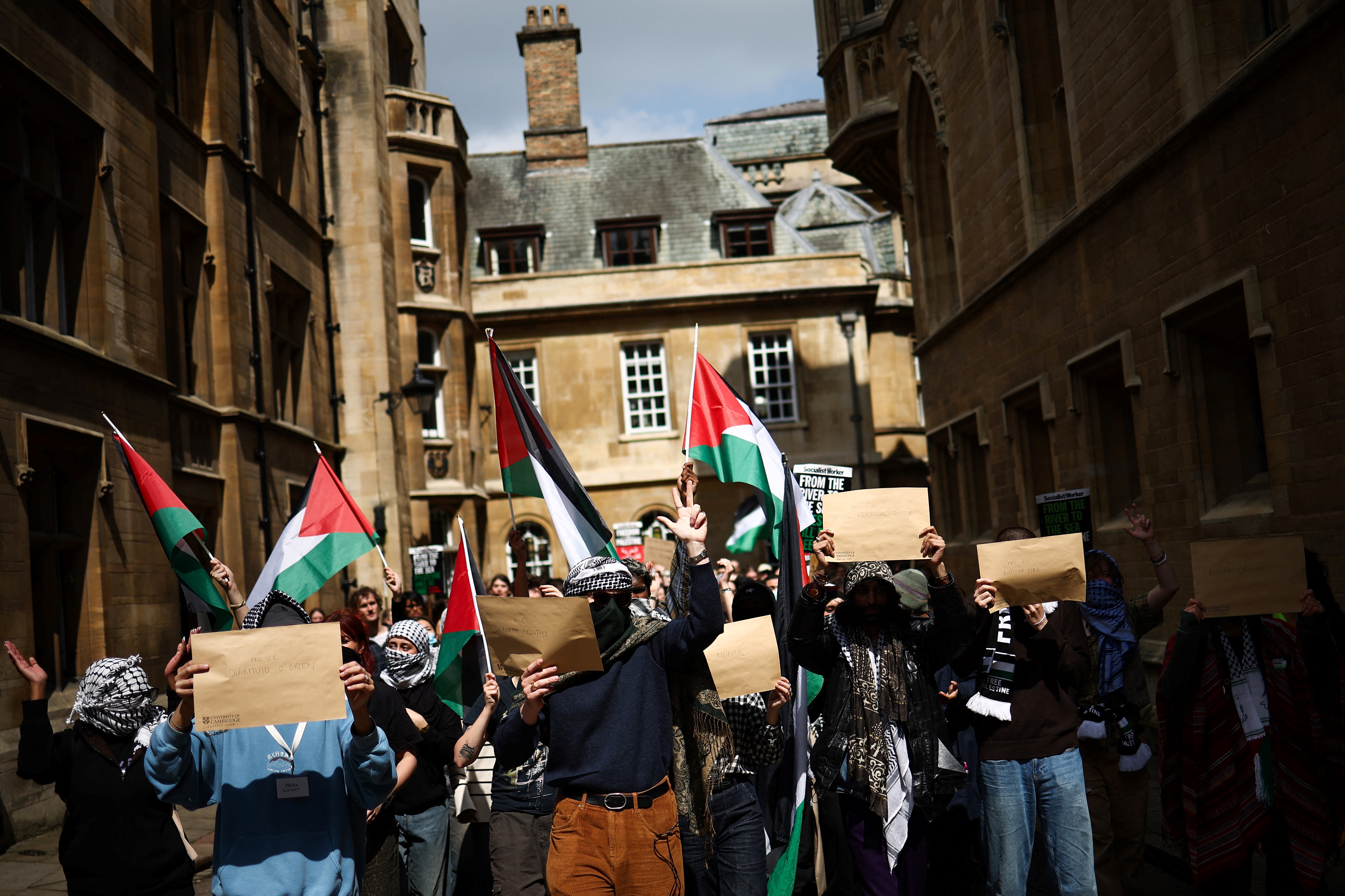 Students wave Palestinian flags as they march towards the Old School buildings to hand letters with their demands to the College Secretary during a protest in support of Palestinian people at Cambridge University