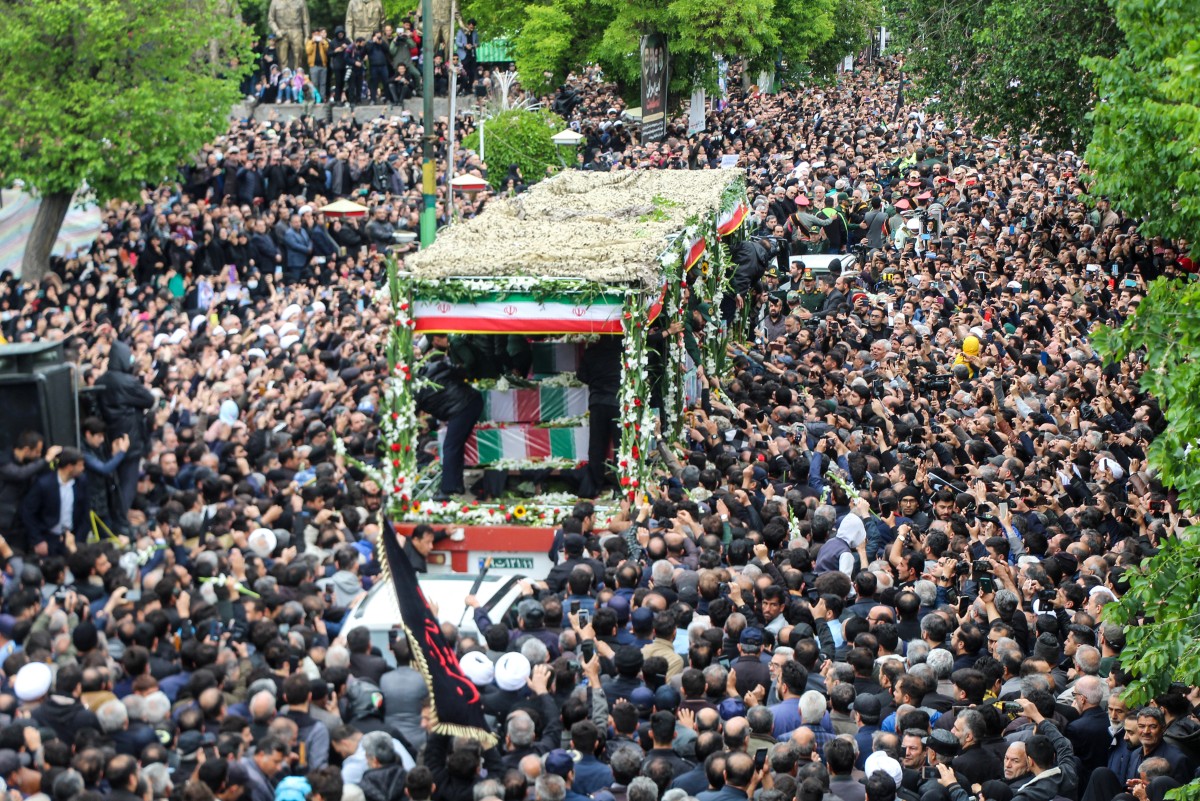 People participate in a funeral procession alongside a truck carrying the coffins of President Ebrahim Raisi and his seven aides in Tabriz, East Azerbaijan province, on May 21