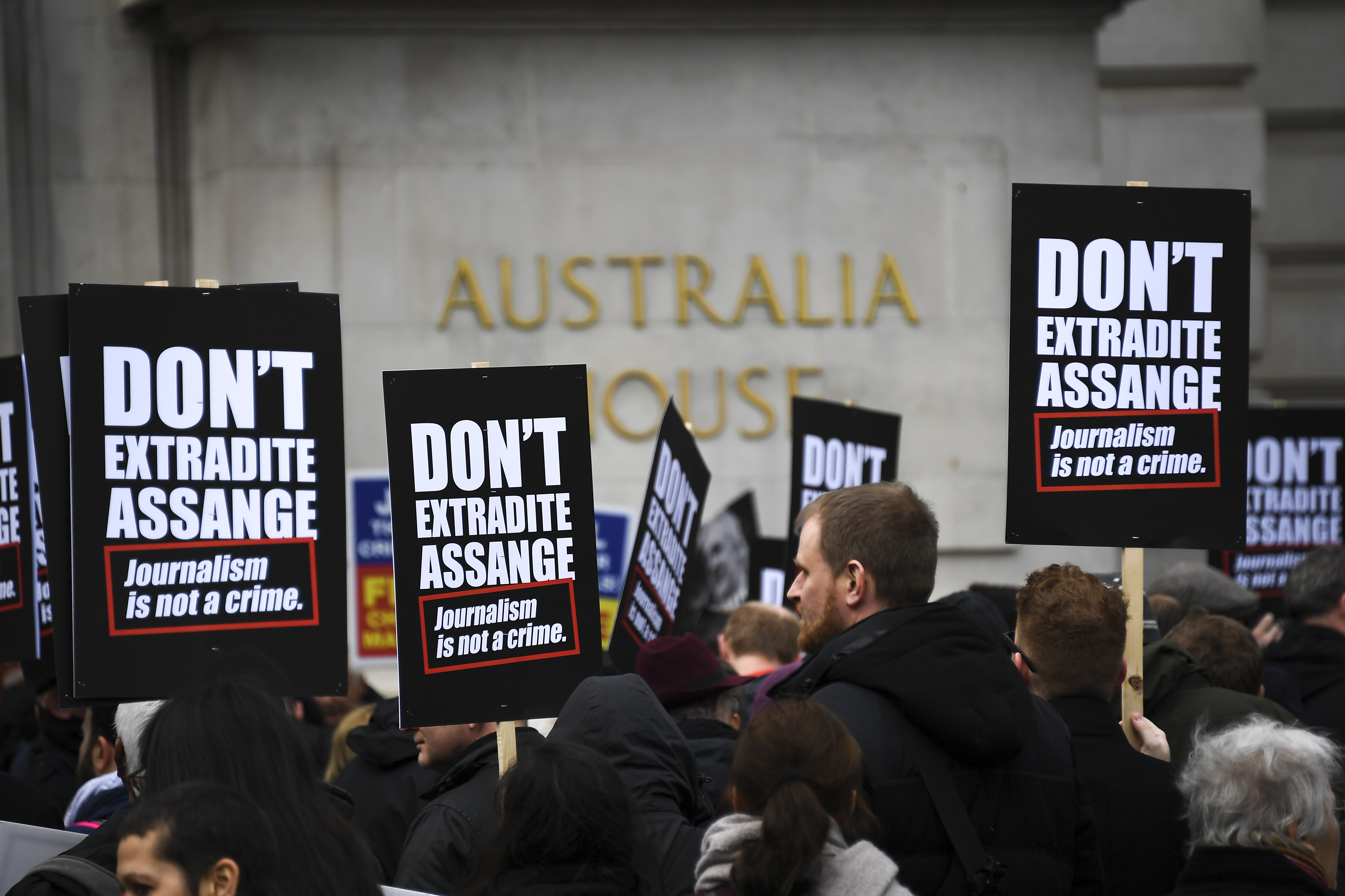 people hold signs saying don't extradite Assange