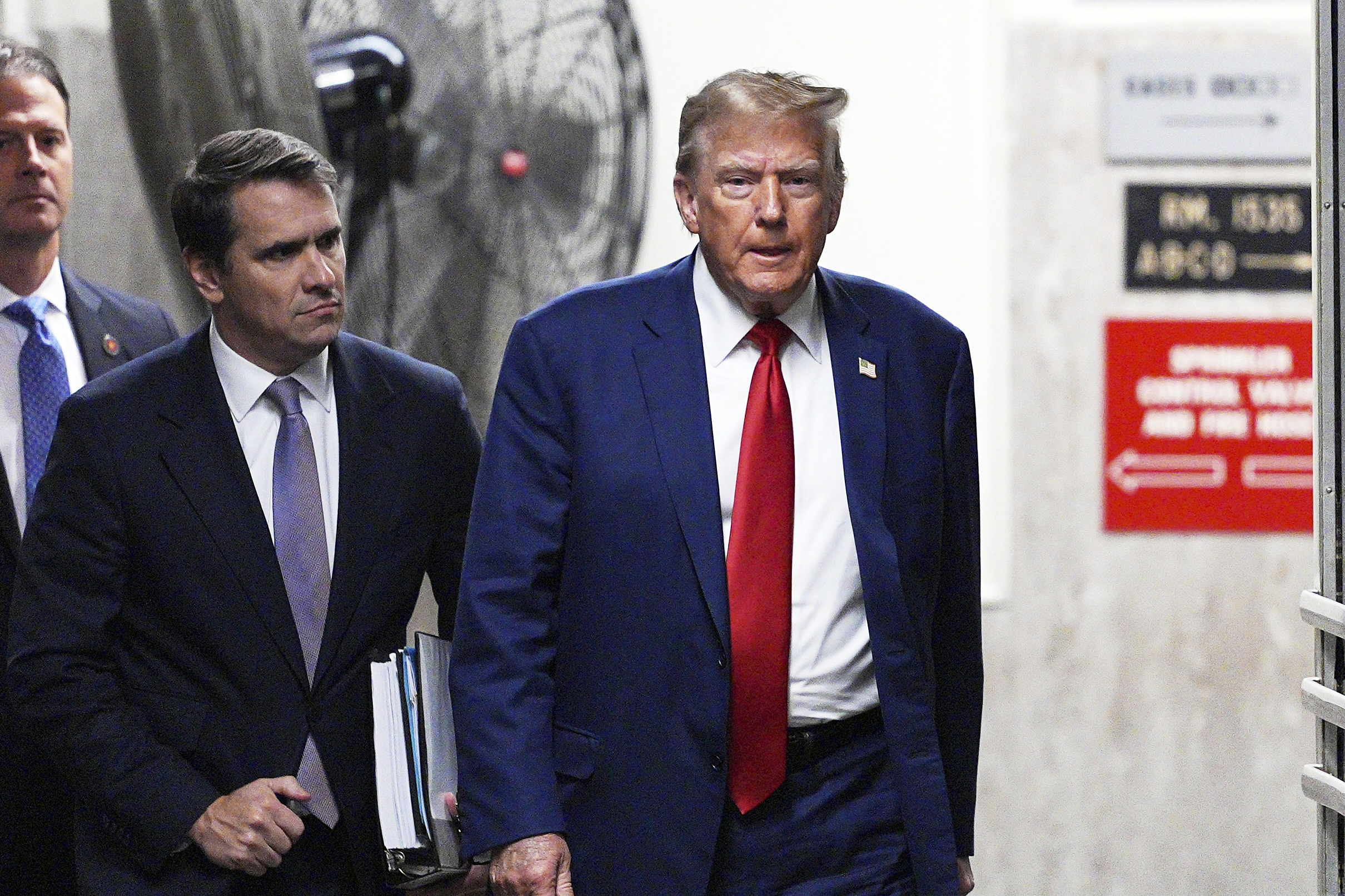 Donald Trump, wearing a blue suit and red tie, walks into the Manhattan criminal courthouse.