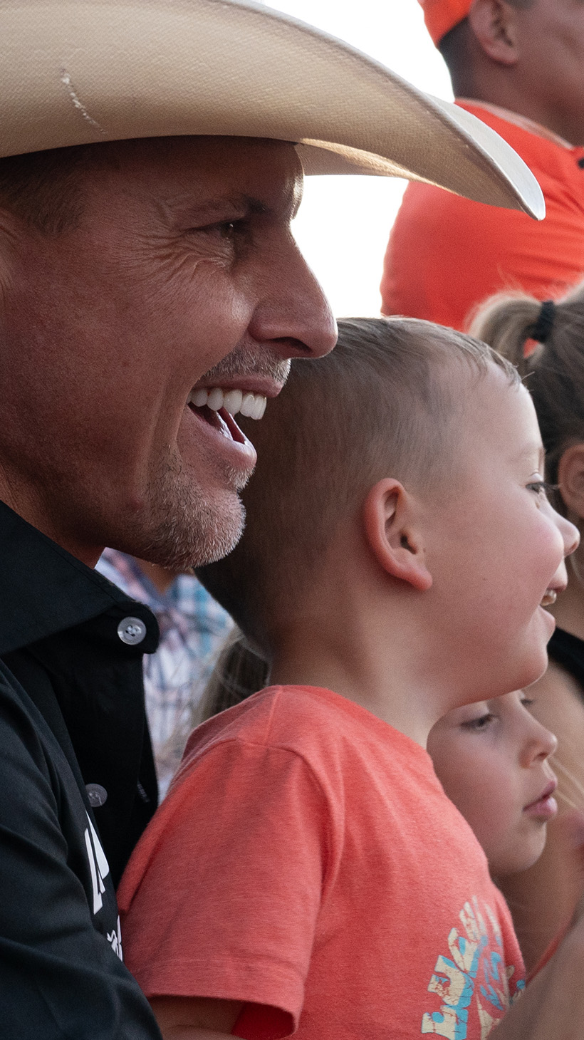 Bryan LeBaron and his family clap as they watch a rodeo.