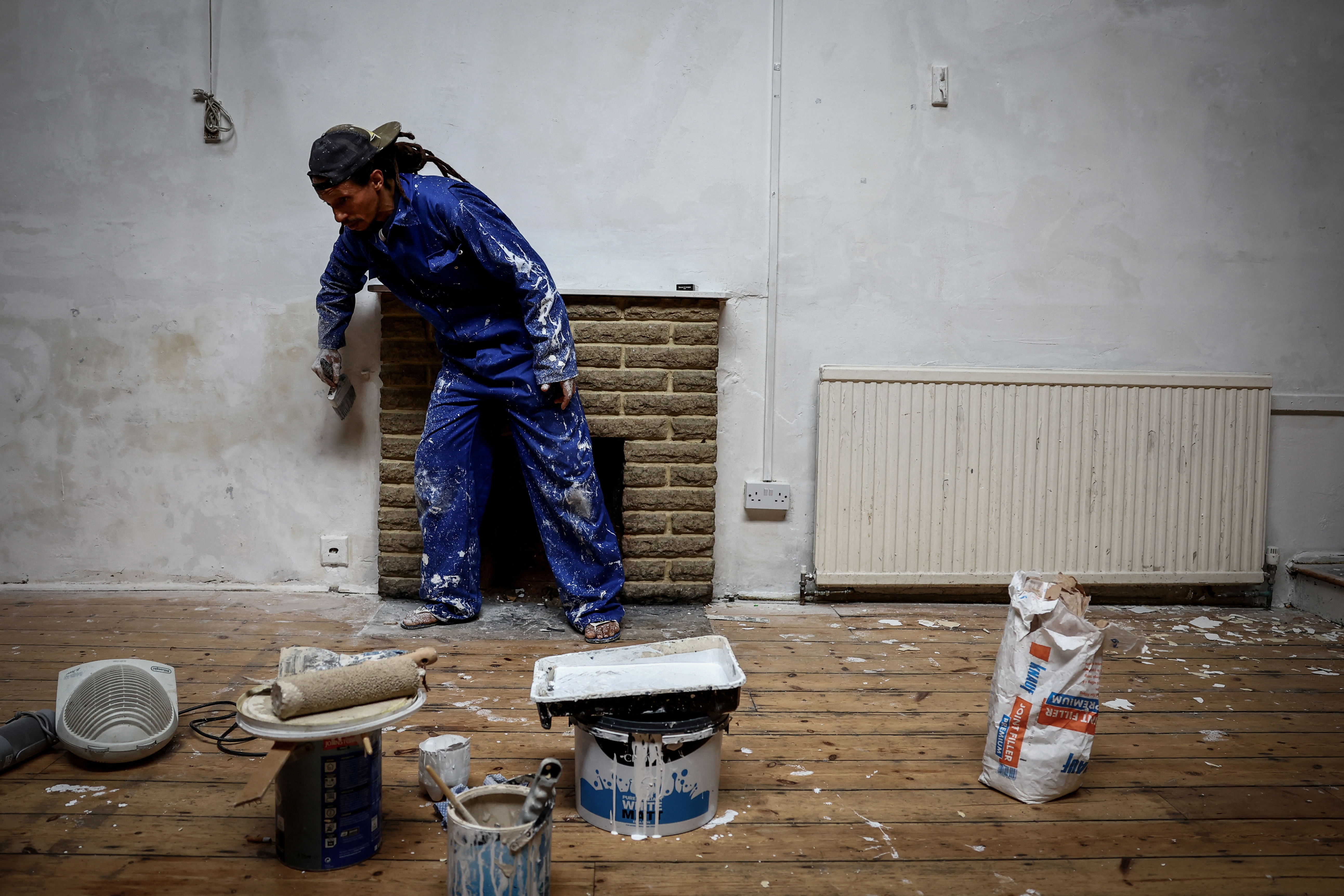 Zin, 47, paints a wall in the area used as a common room of the place he lives, which was once a school and is now occupied by squatter activist group Reclaim Croydon, in Croydon, south London, Britain, May 16