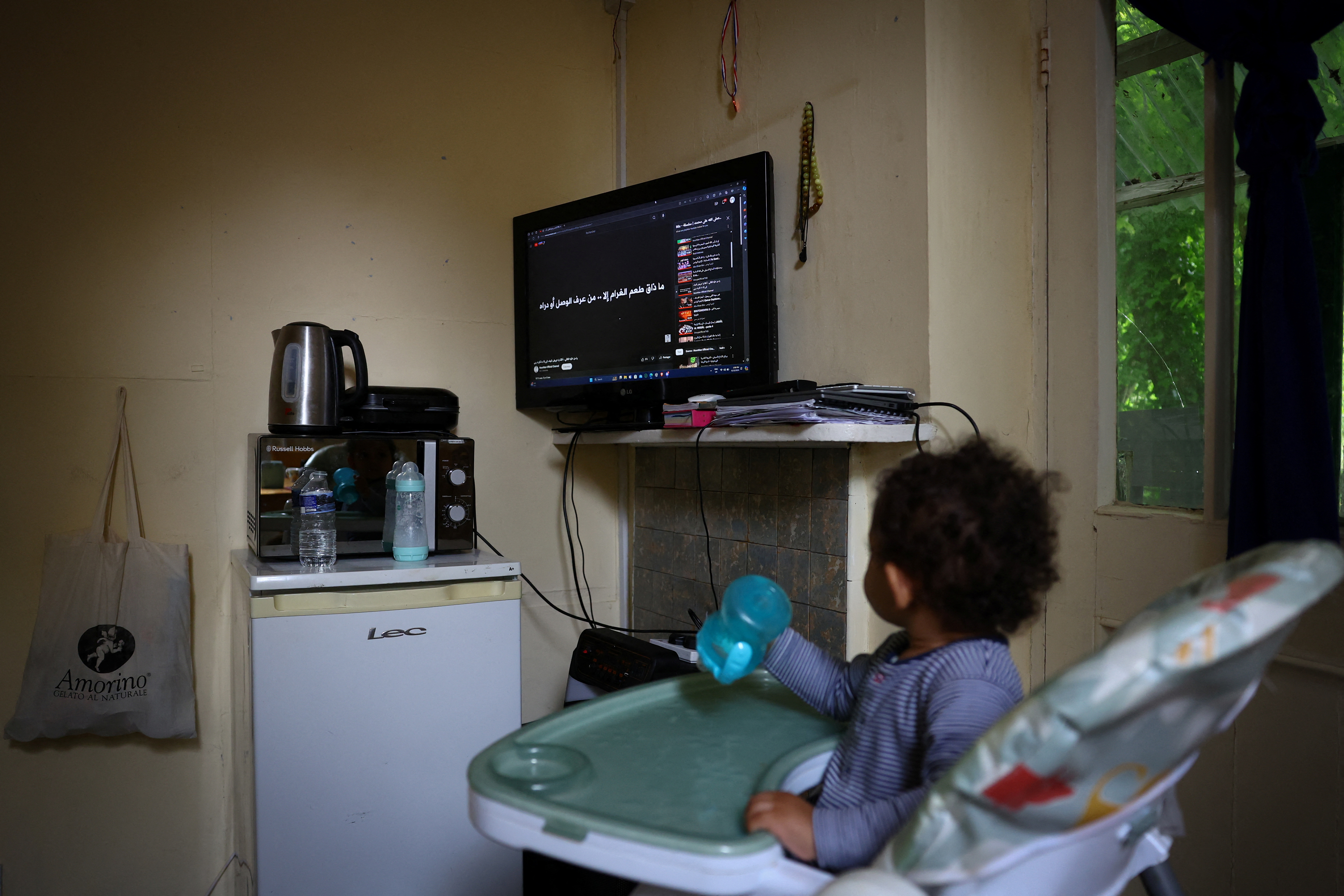 A child watches TV from his highchair in the space he lives in which was once a school and is now occupied by squatter activist group Reclaim Croydon, in Croydon, south London, Britain, June 13