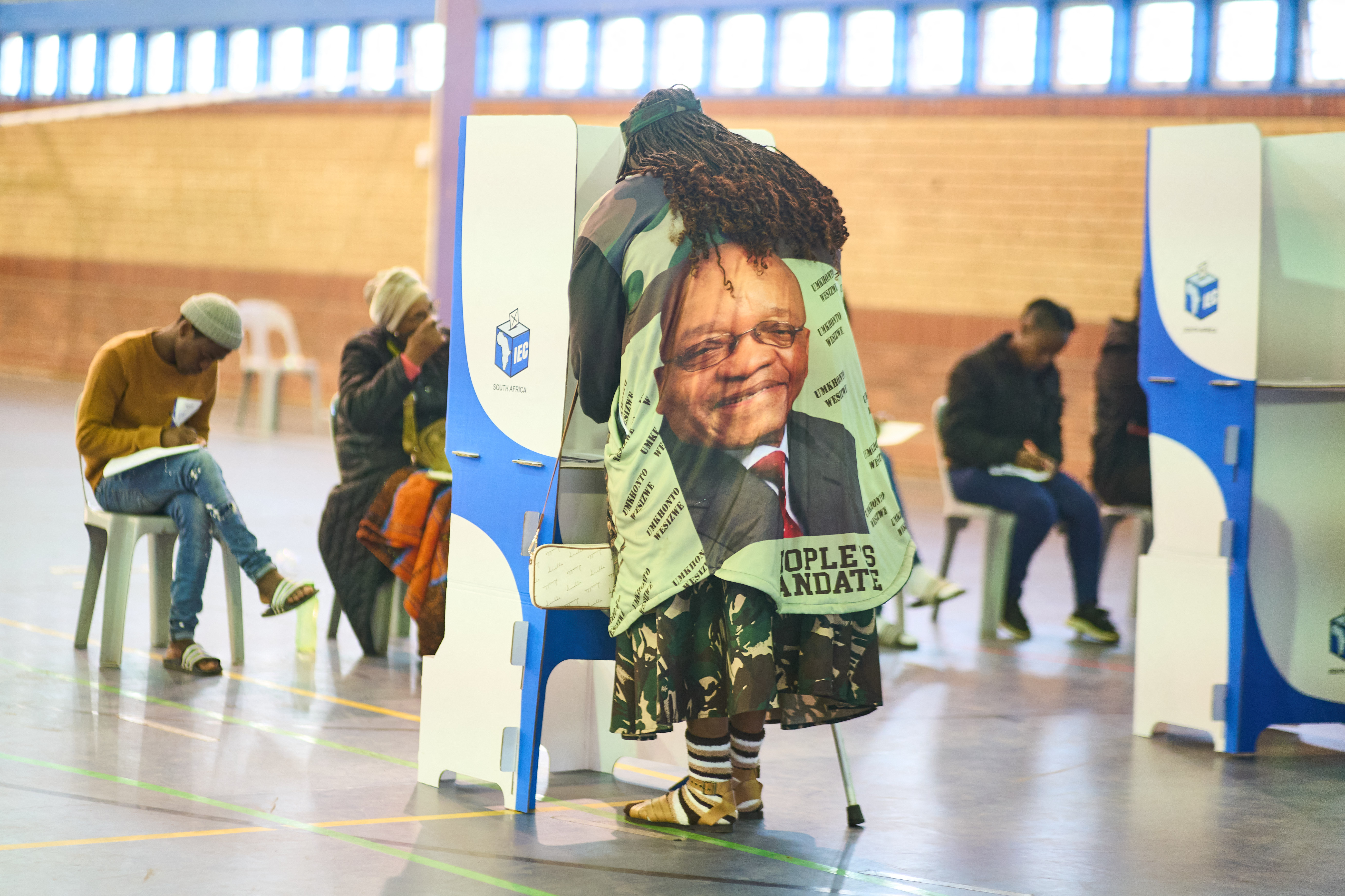 A voter wearing a shirt of former South African President and uMkhonto weSizwe (MK) leader Jacob Zuma on, marks her ballots in a voting booth at a polling station in Umlazi on May 29