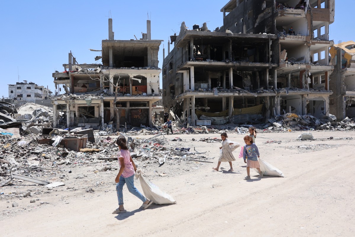 Palestinians walks next to destroyed buildings in the Jabalia