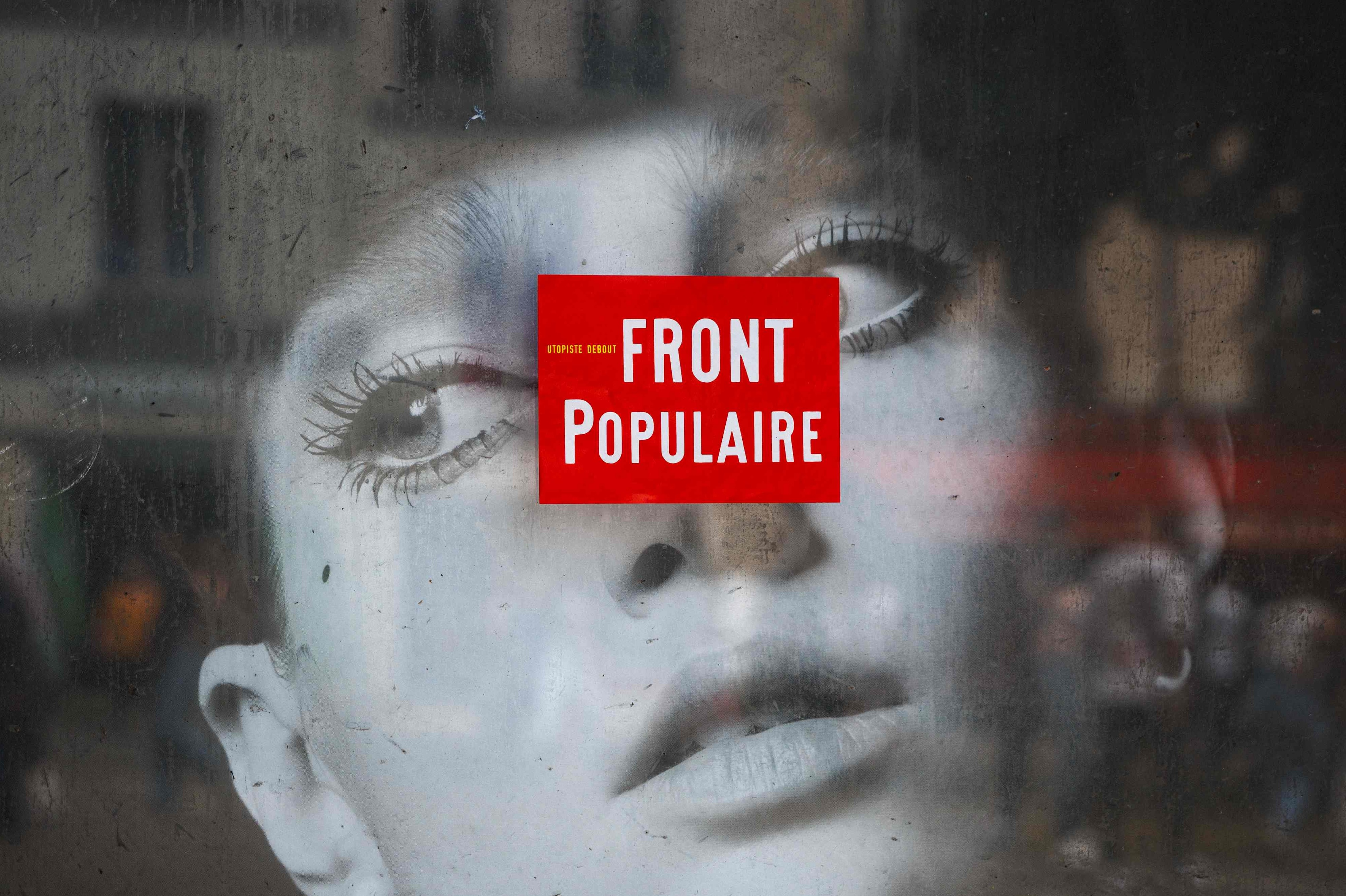 This photograph shows a campaign sticker of the left-wing coalition Nouveau Front Populaire (New Popular Front - NFP) displayed on a poster, two days ahead of the first round of France's upcoming legislative elections in Paris on June 27, 2024 [Dimitar Dilkoff/AFP]