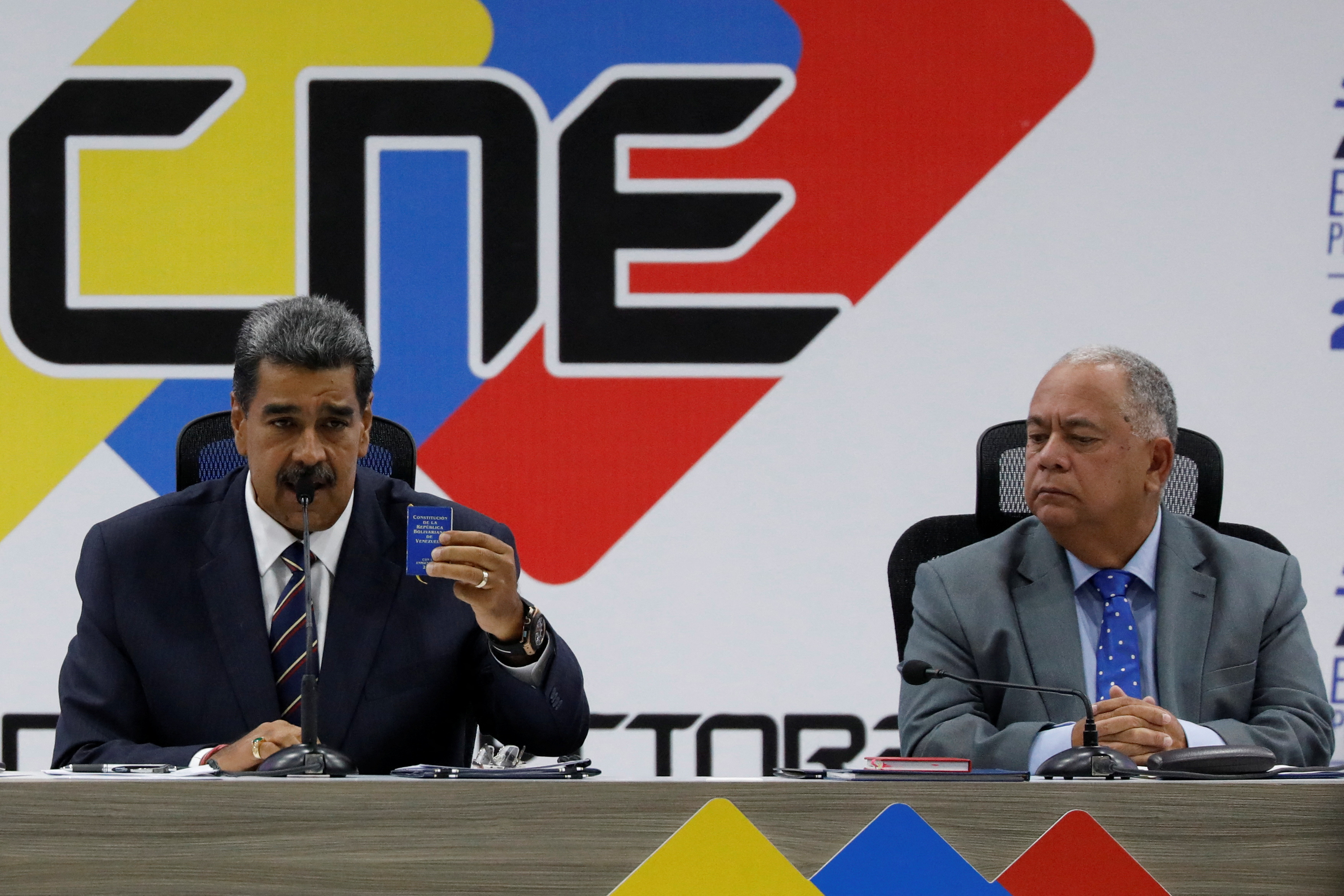 Nicolas Maduro sits next to the head of Venezuela's electoral authority Elvis Amoroso