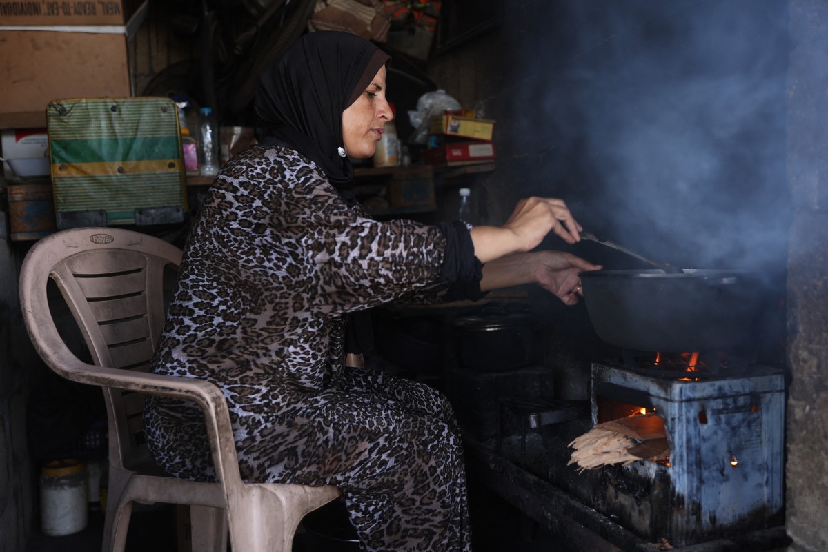 A Palestinian woman cooks for her family at their home in the Sheikh Radwan neighbourhood