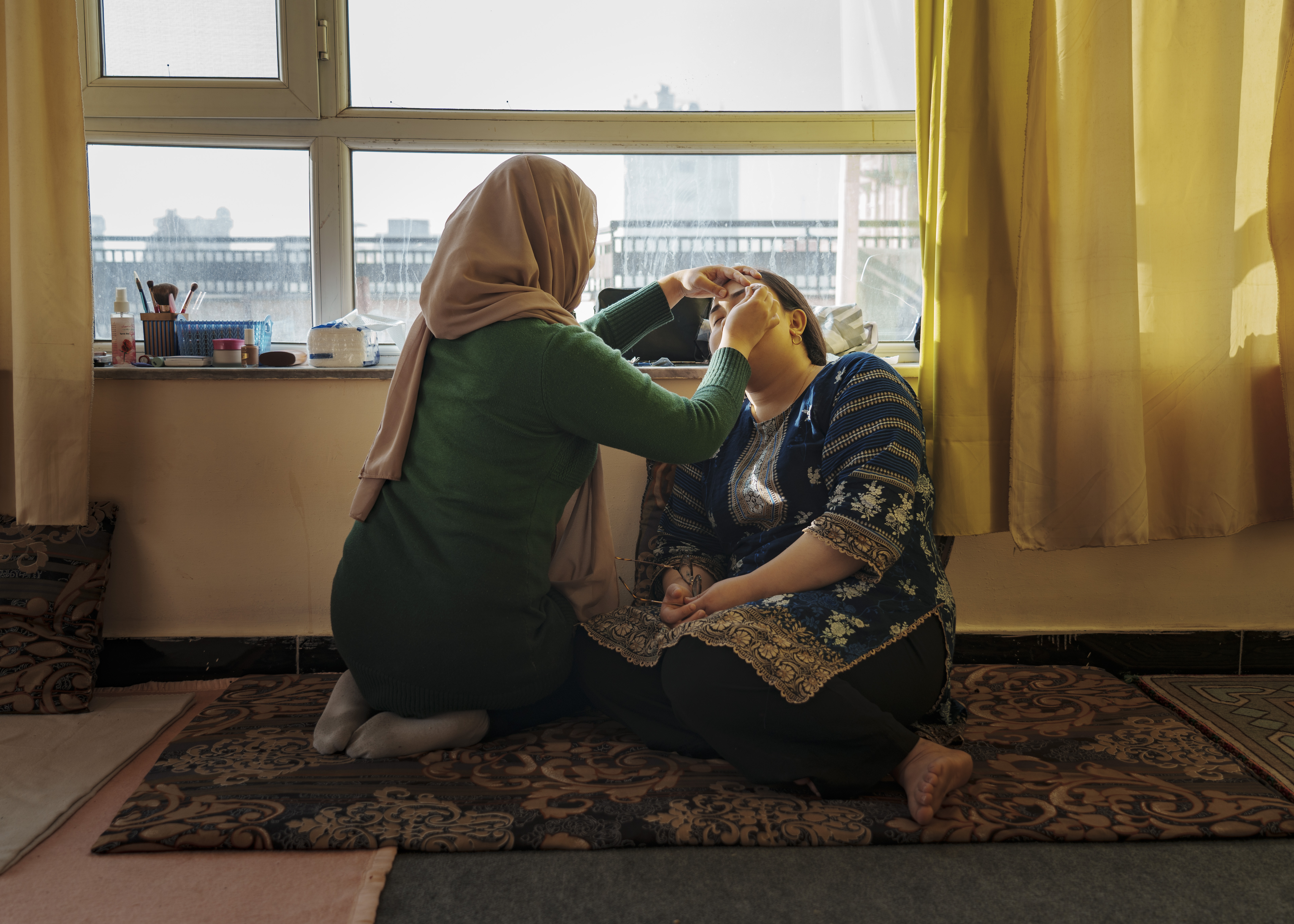 Sabba, 27, has her eyebrows waxed at home by Leila, her beautician. [Sandra Calligaro/Al Jazeera]