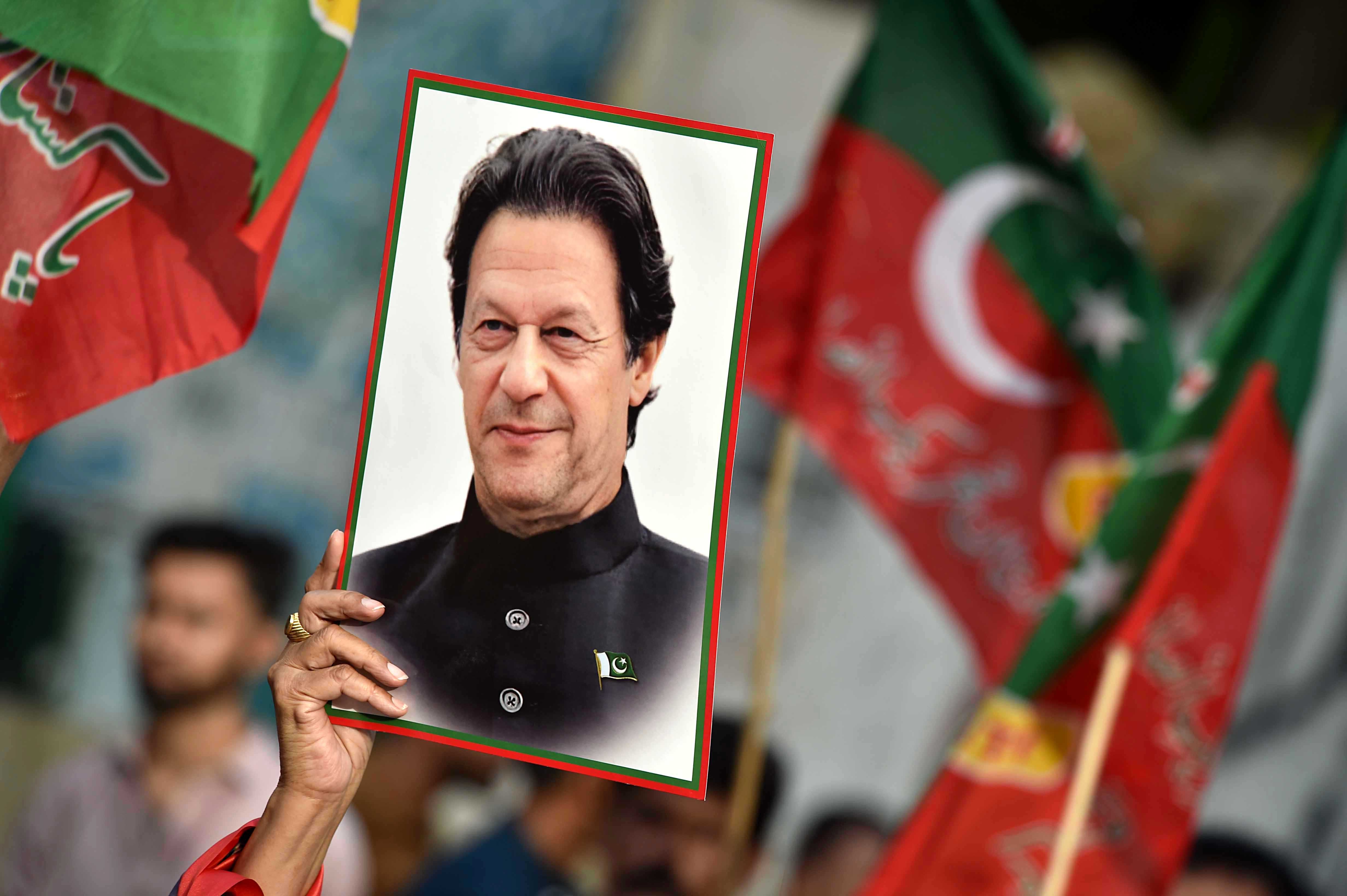 A supporter holds a portrait of Imran Khan.