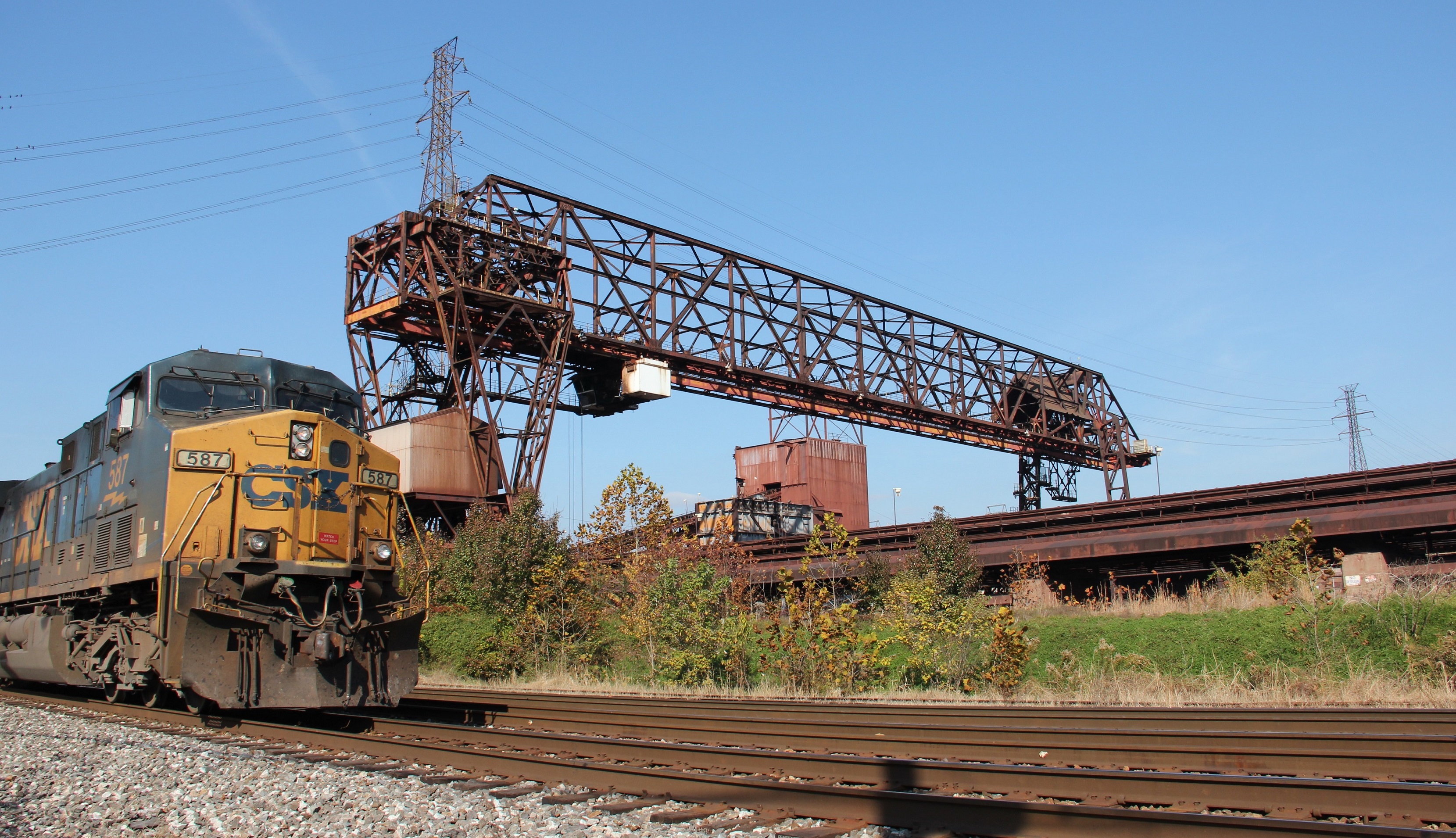 A steel plant near the Ohio River in Kentucky is visible across a set of train tracks.
