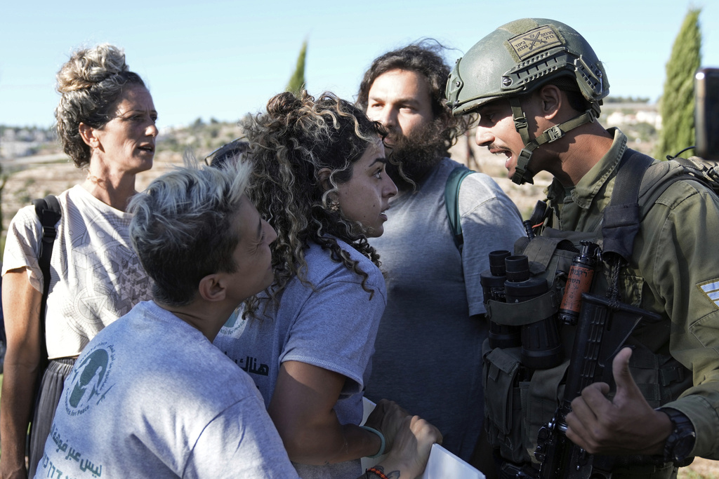 Israeli activists surround Alice Kisiya, center, as they try to enter her family's land, after the Palestinian family was forcefully evicted by Israeli settlers backed by soldiers who declared it a closed military area, in the West Bank town of Beit Jala, Friday, Aug. 2, 2024. (AP Photo/Mahmoud Illean)