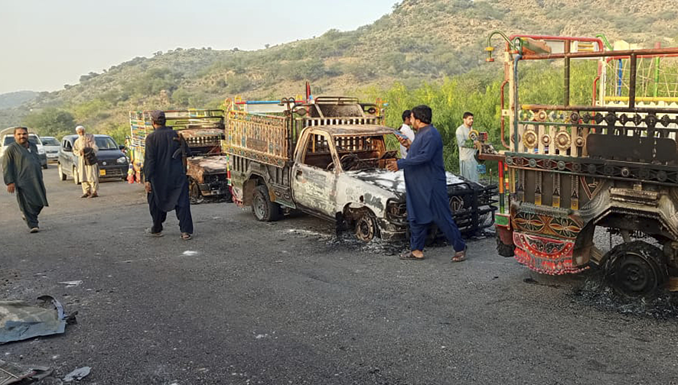 People look burnt vehicles, torched by gunmen after killing passengers, at a highway in Musakhail, a district in Baluchistan province in southwestern