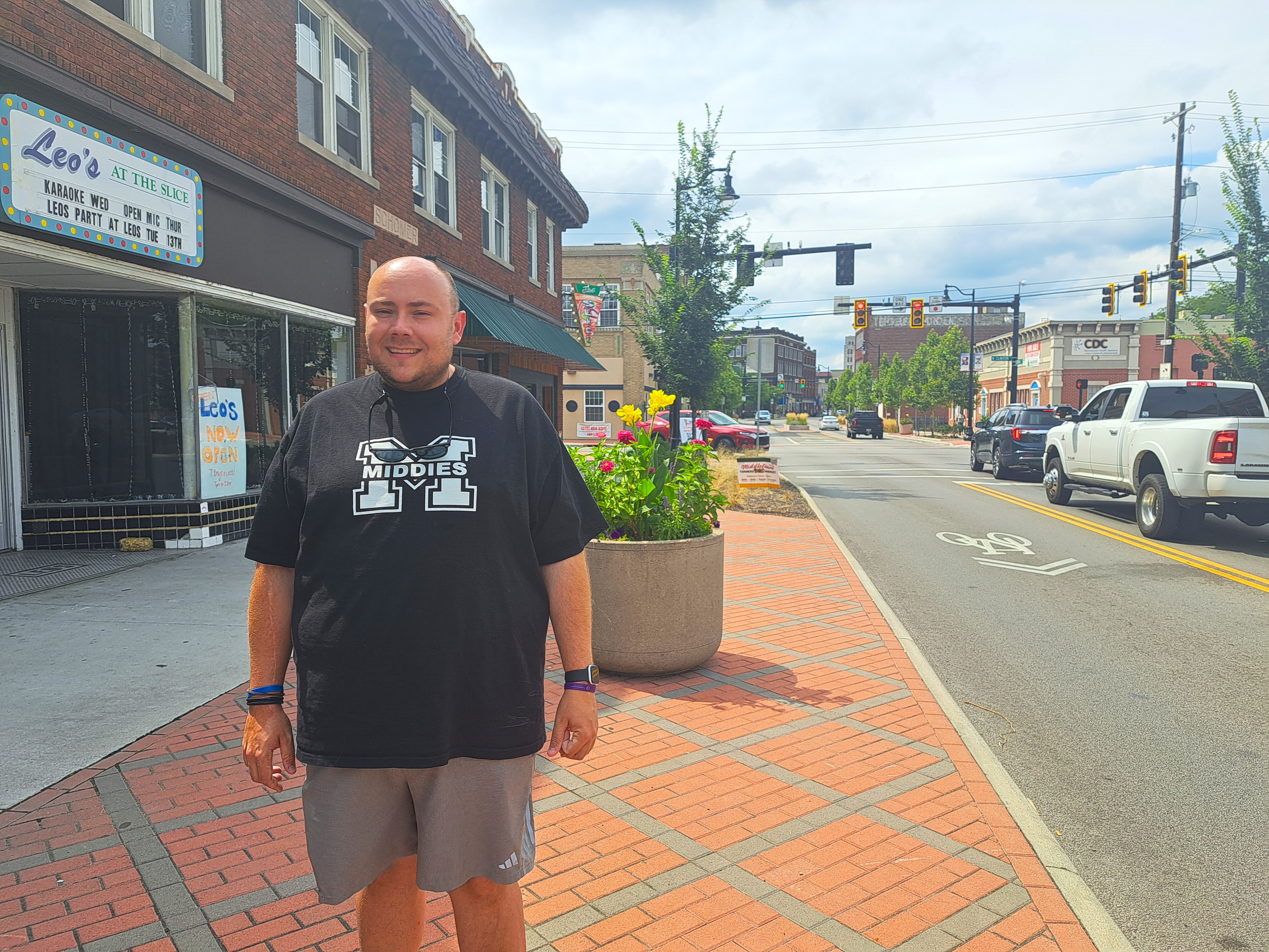 Scotty Robertson, dressed in a black T-shirt and shorts, stands on a Middletown street.