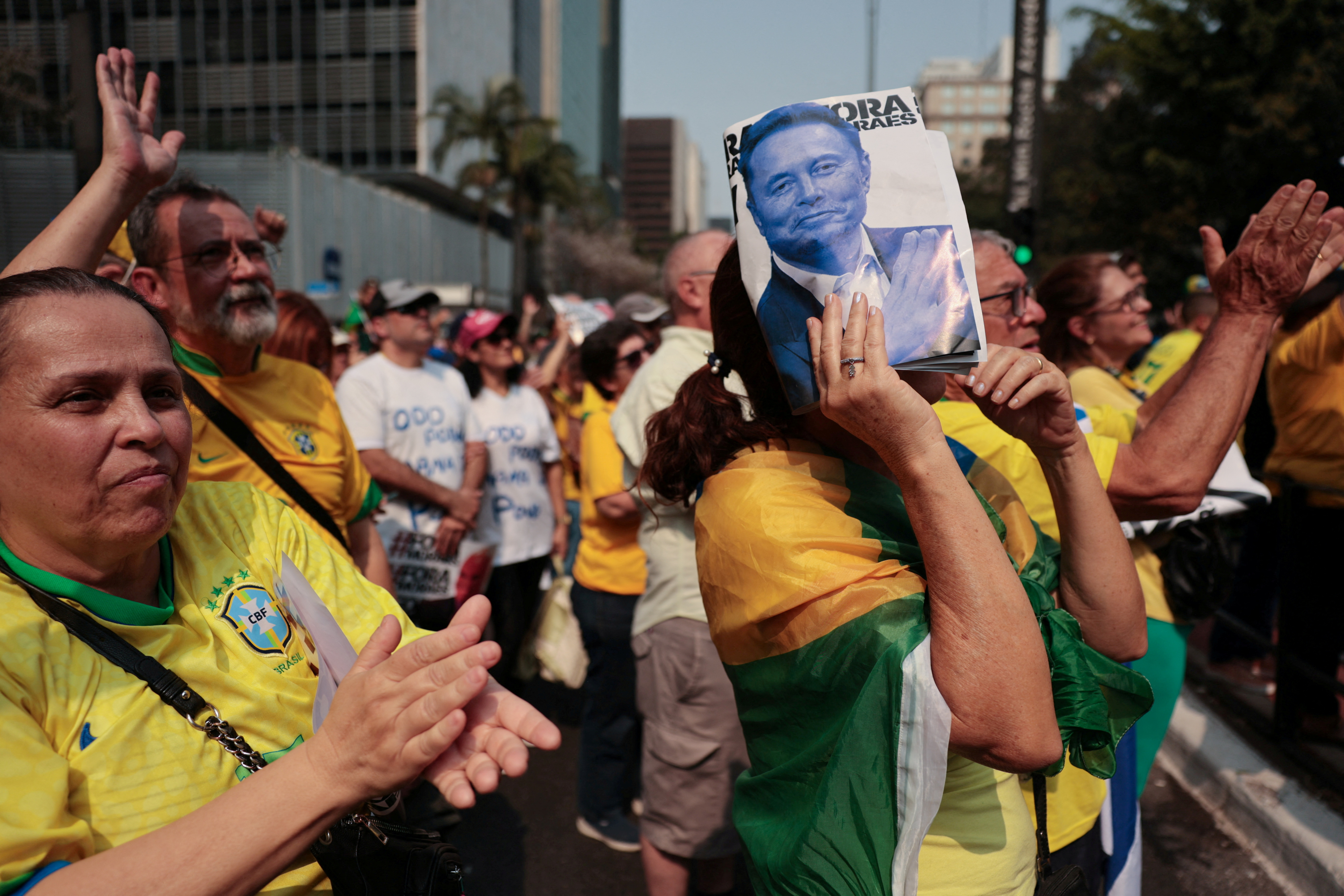 A protester in Brazil holds up a picture of Elon Musk.