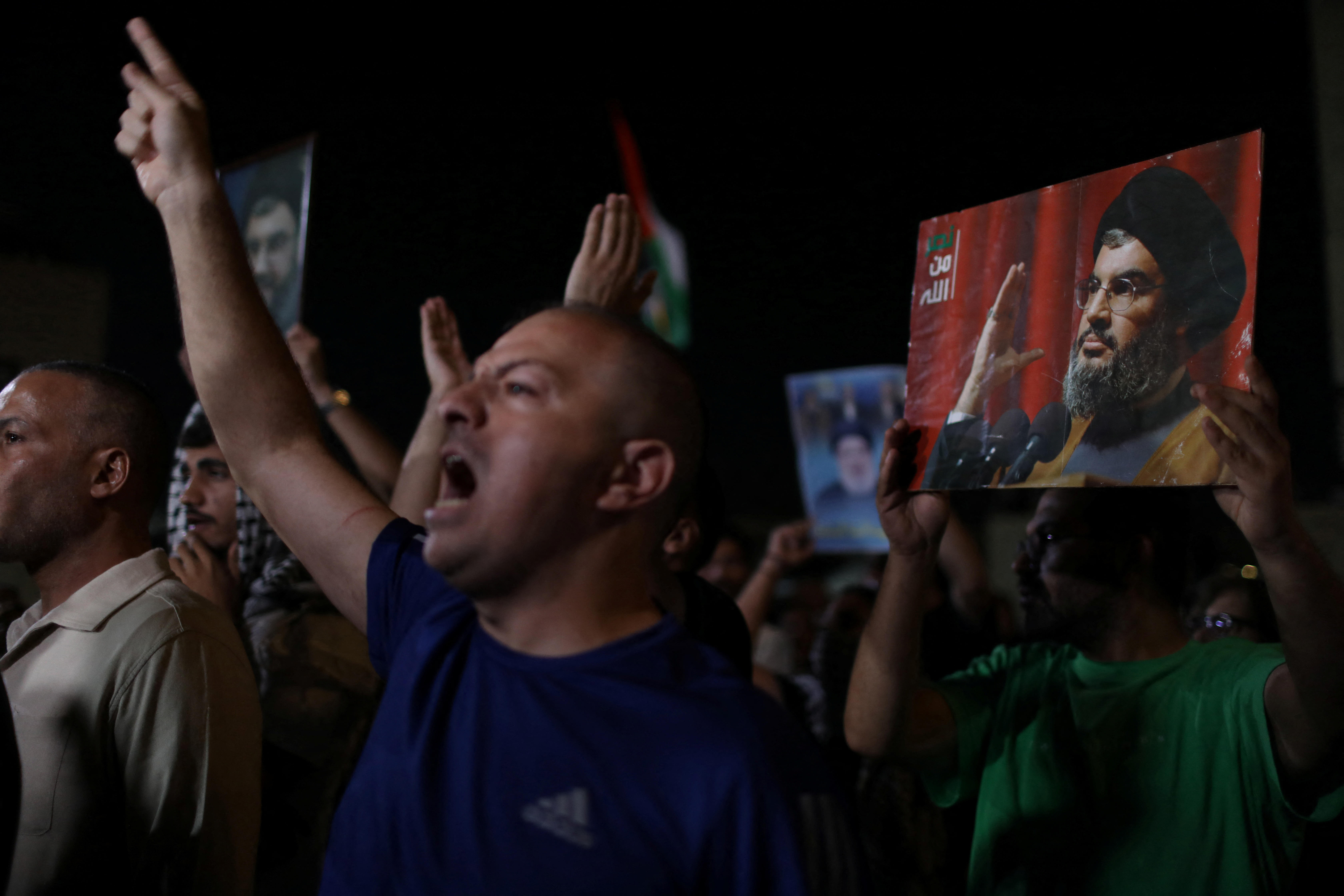 Demonstrators gesture as they carry pictures of Lebanon's Hezbollah leader Sayyed Hassan Nasrallah during a protest, following his killing in an Israeli airstrike in Beirut's southern suburbs on Friday, outside Al Kalouti mosque near the Israeli embassy in Amman