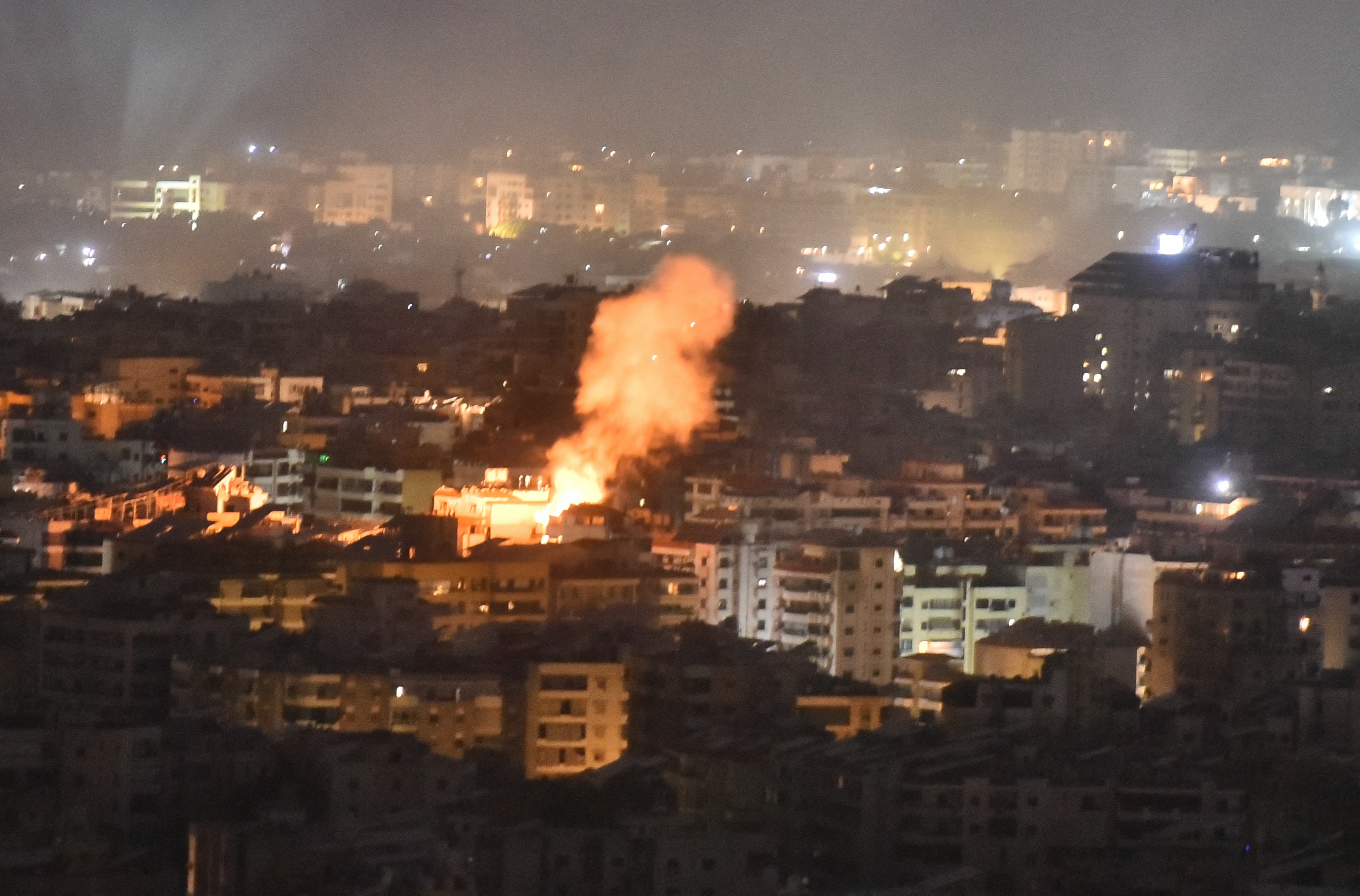 Smoke rising from an Israekie air attack on a southern suburb of Beirut. It's dark. There are lots of multi-storey apartment blocks