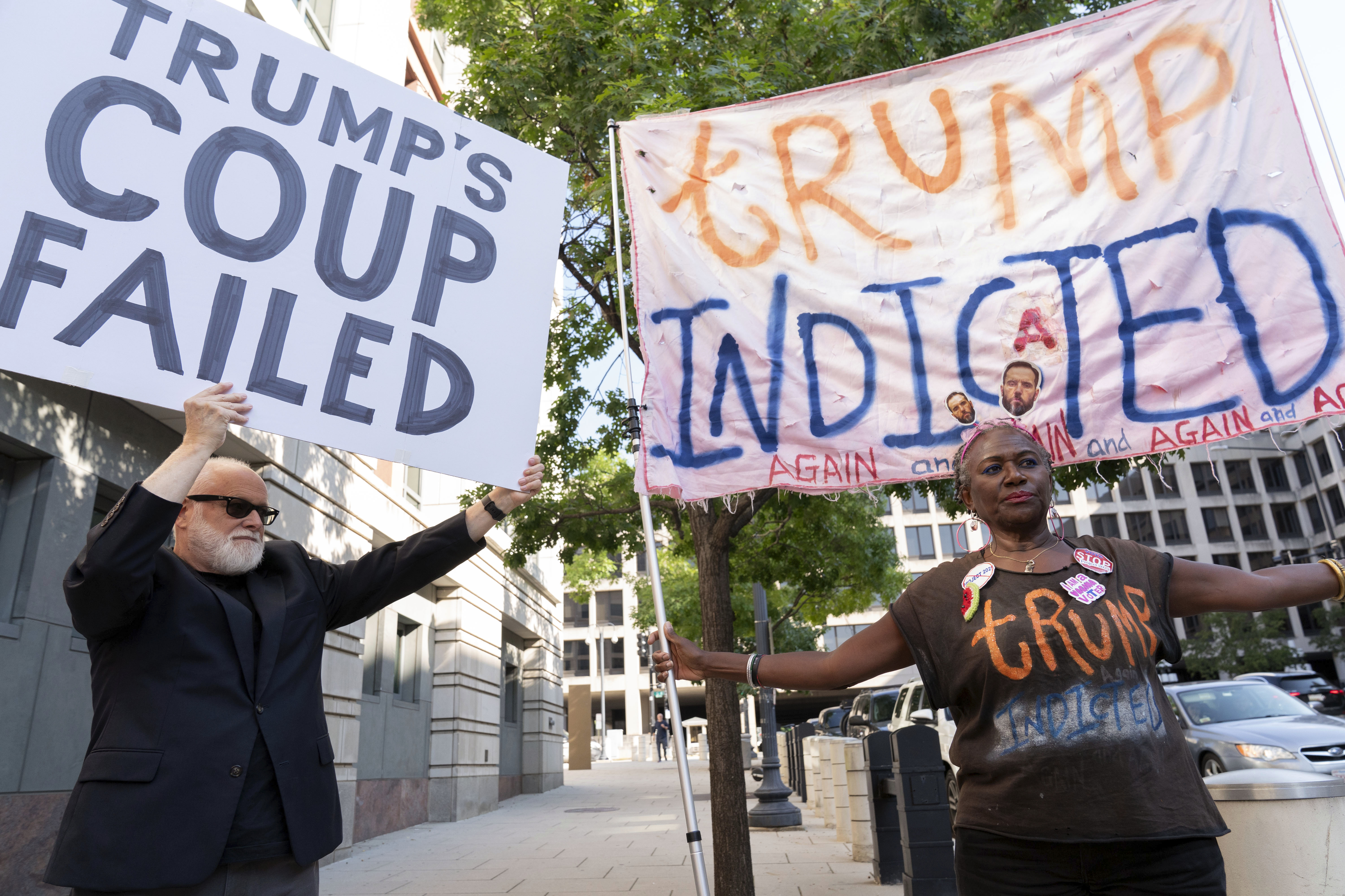 Protesters in Washington, DC, hold up signs that read "Trump's coup failed" and "Trump indicted."